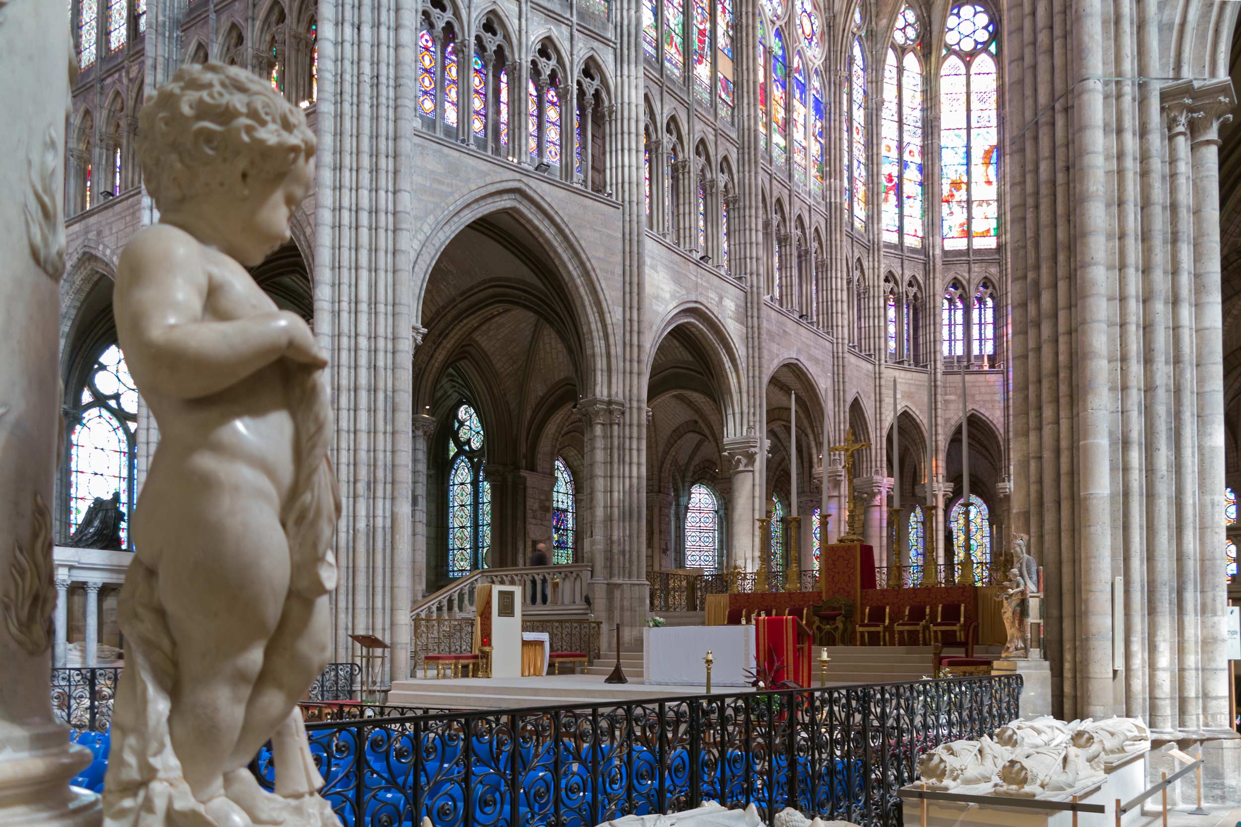 Stained glass windows, arches and cherubic statues in the interior of a Gothic cathedral