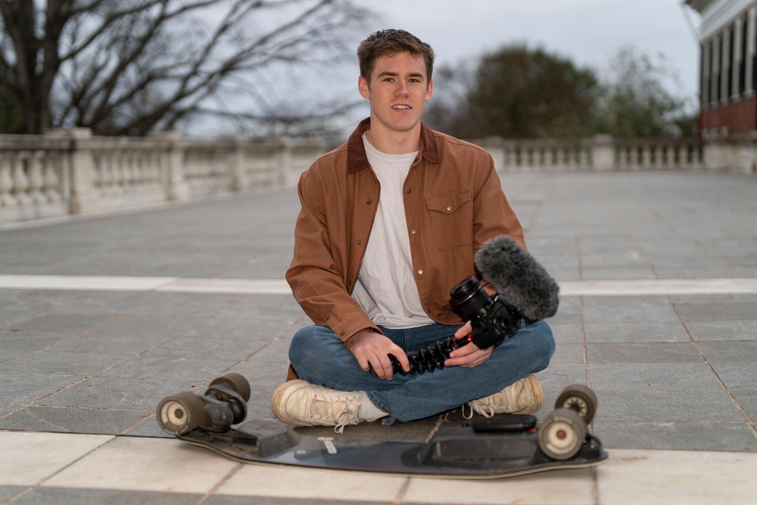 Portrait of Sam White with his skateboard on grounds