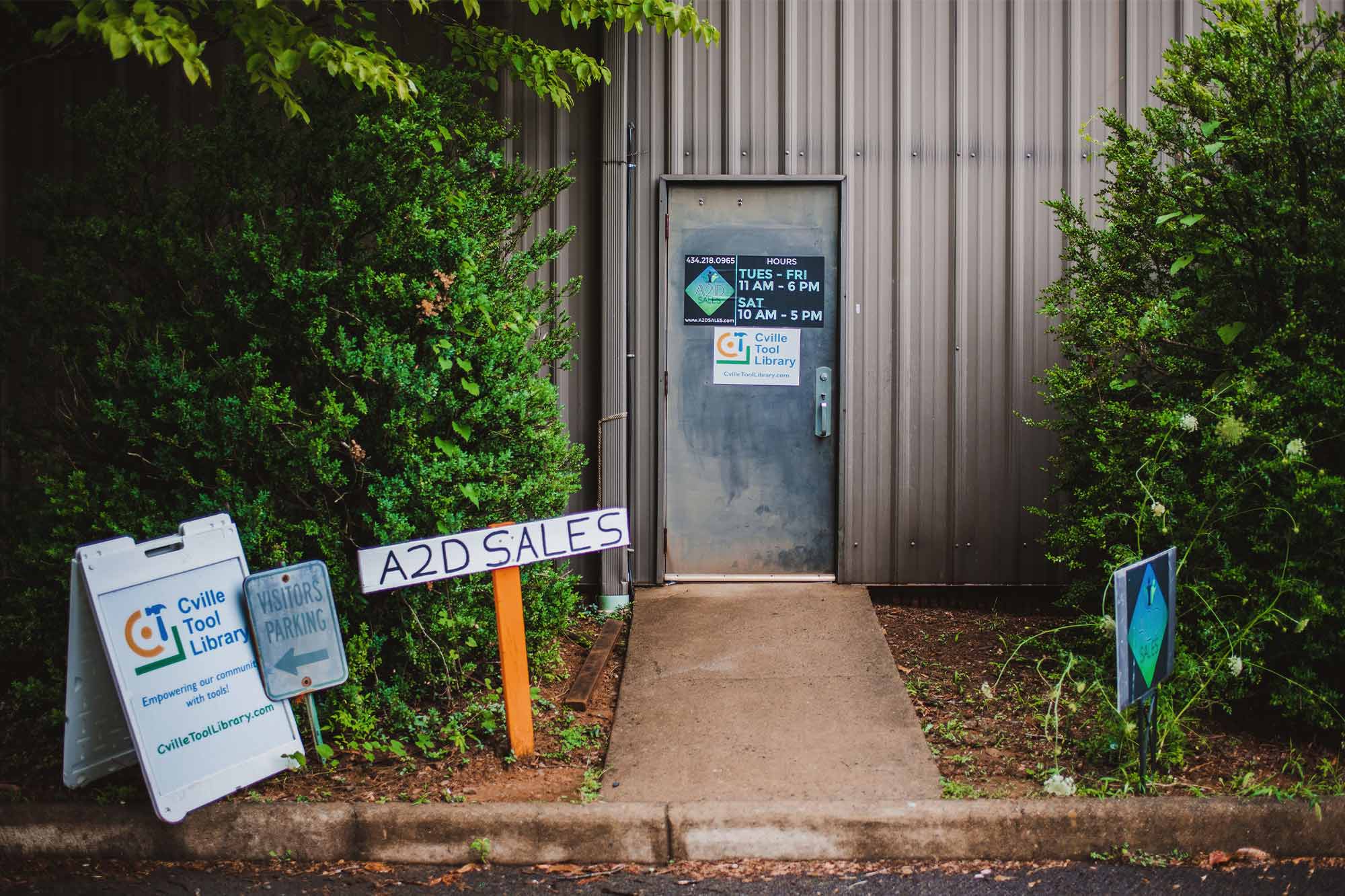 A sign for the Cville Tool Library sits in front of a metal door