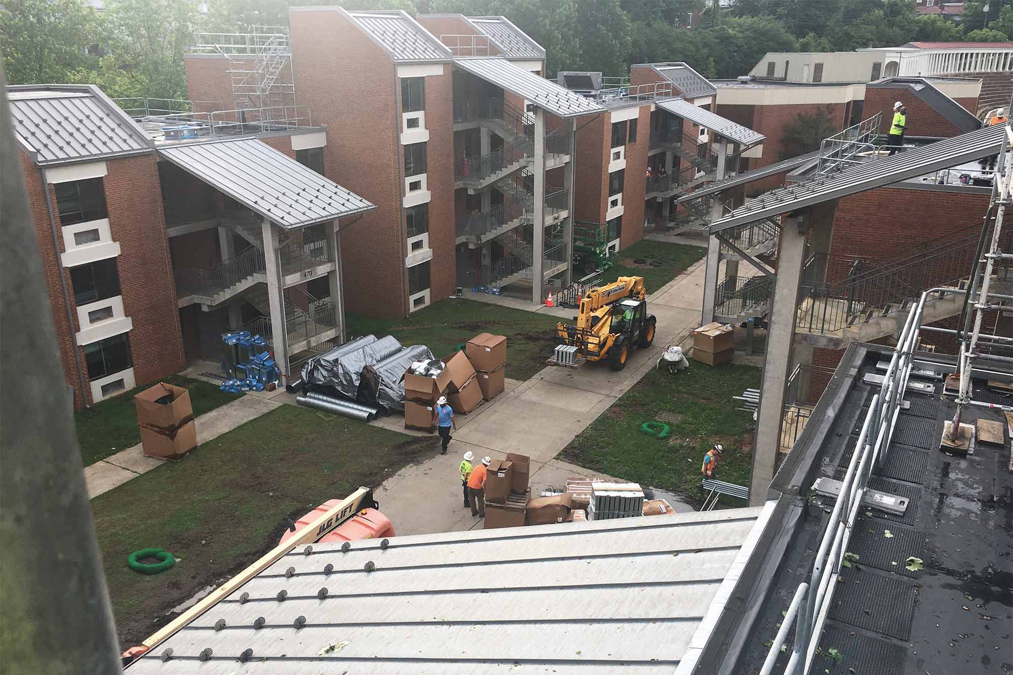 Construction equipment and stacks of boxes and supplies outside student apartment buildings