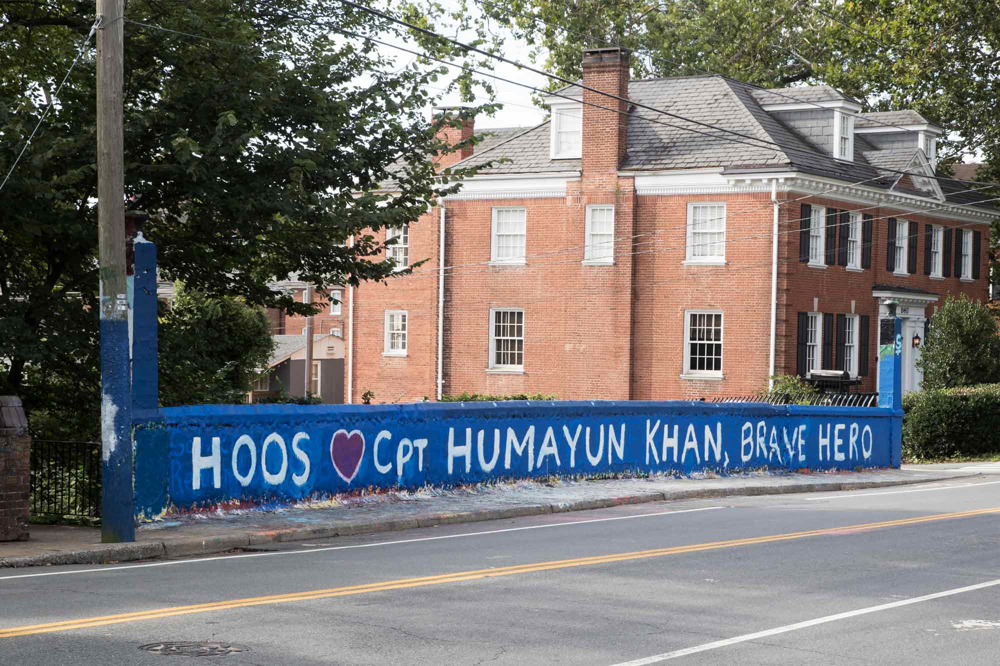 The concrete rail of a bridge is painted blue and reads Hoos Love Captain Humayun Khan, Brave Hero