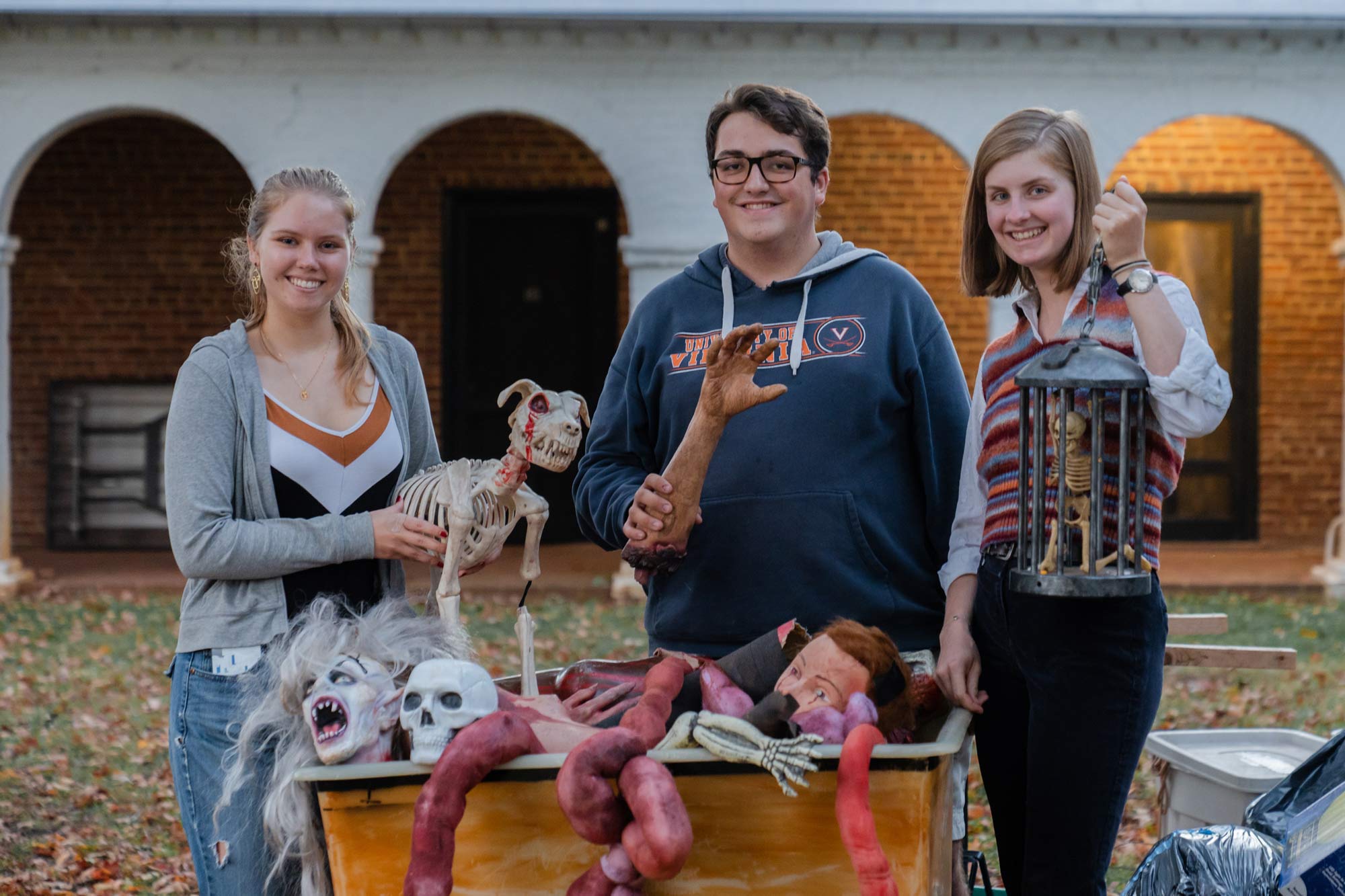 Group photo of three people holding spooky props for the haunted house