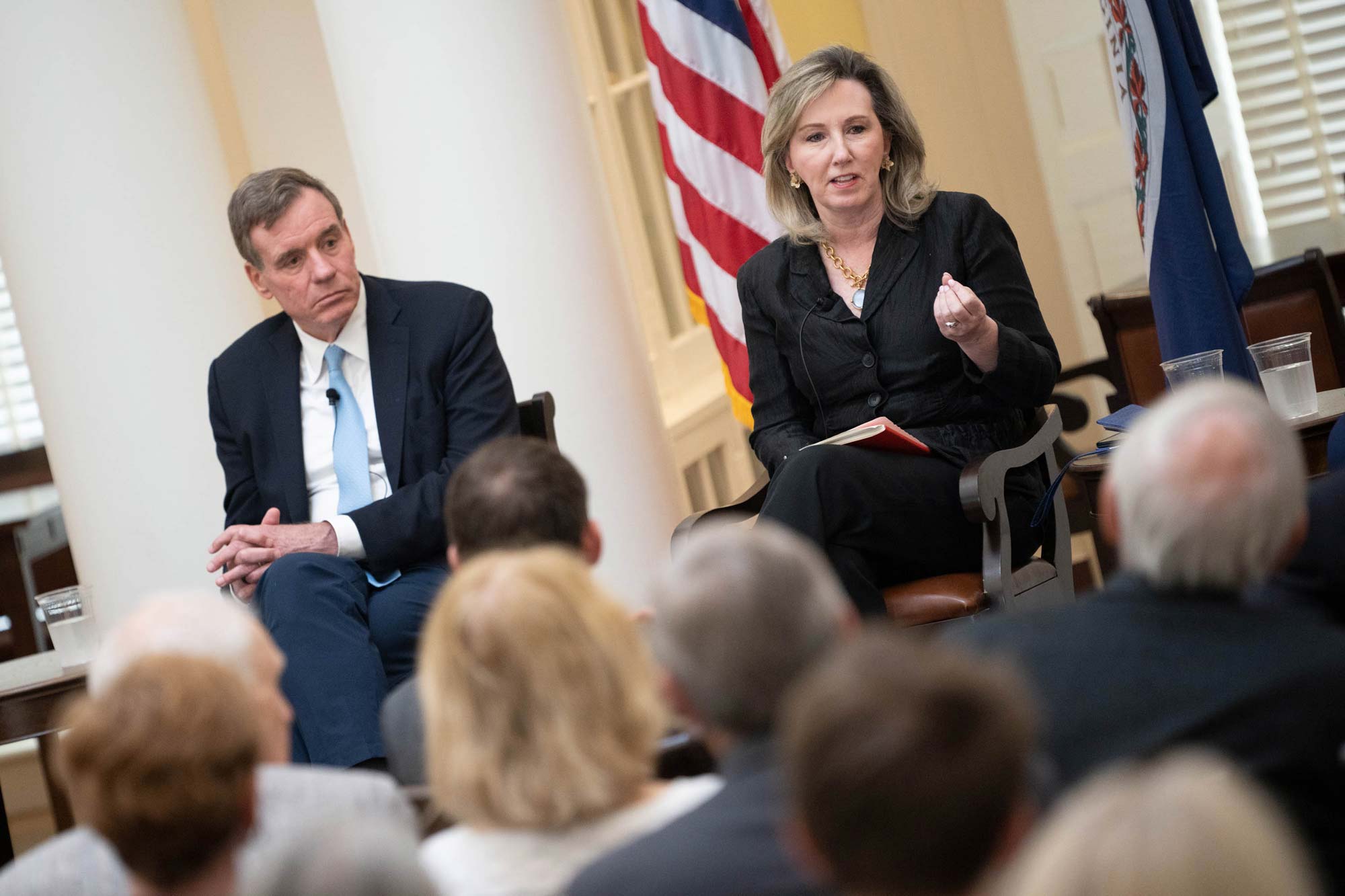 Barbara Comstock, seated next to Mark Warner, speaks to the audience.