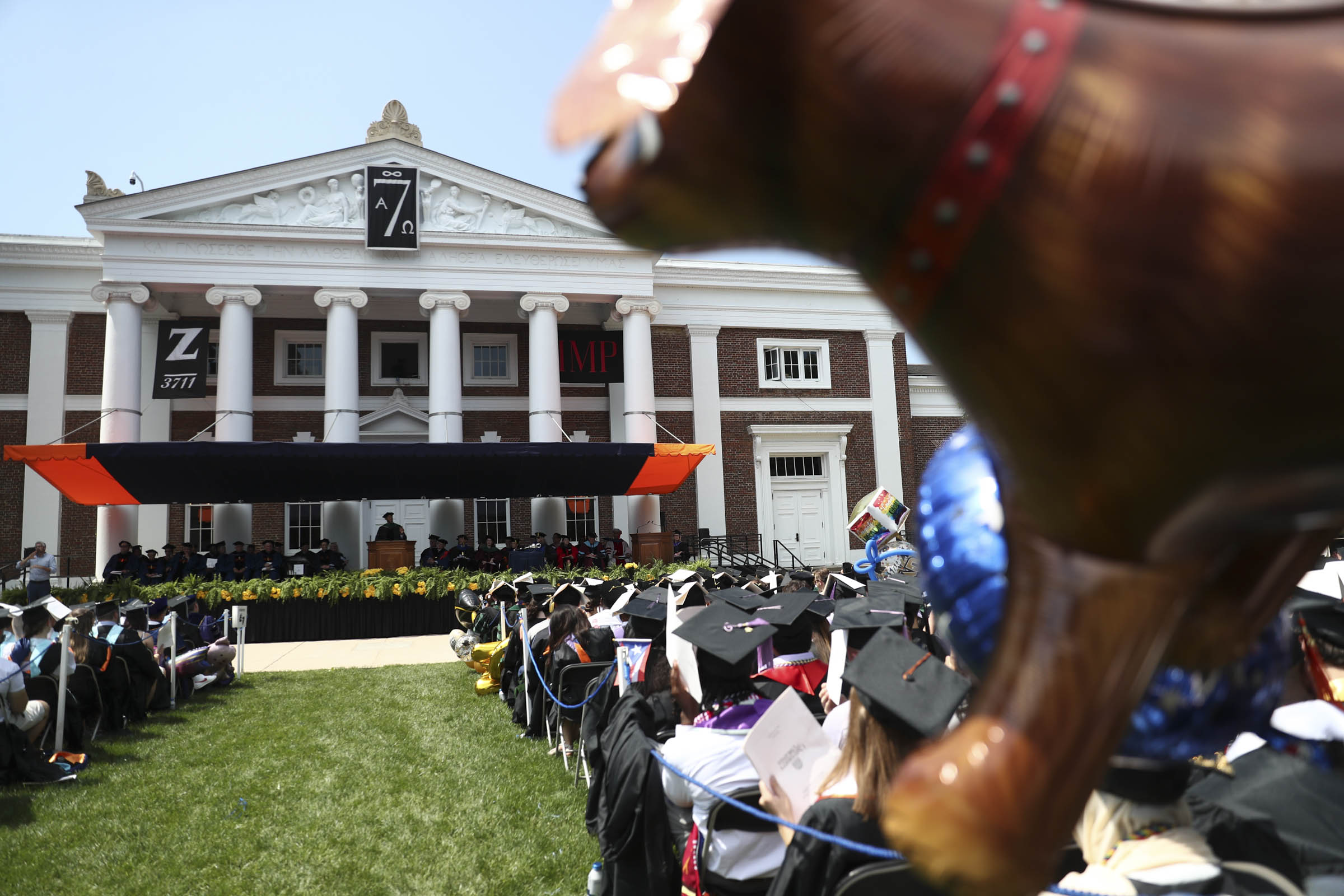 From behind a balloon shaped like a cow, the graduates listen intently to the speaker