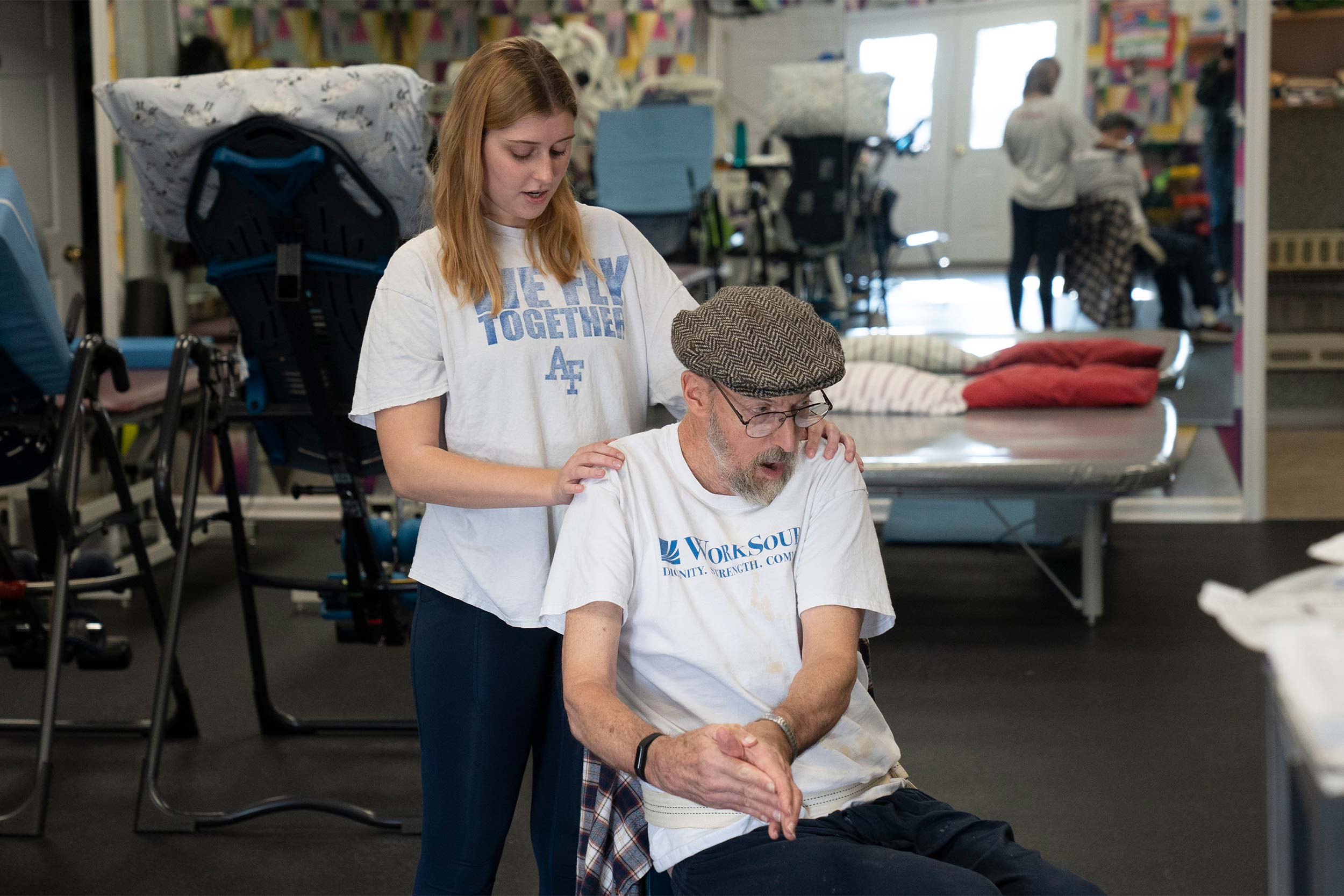 Intern holding a patients shoulders as he does an exercise from a chair.