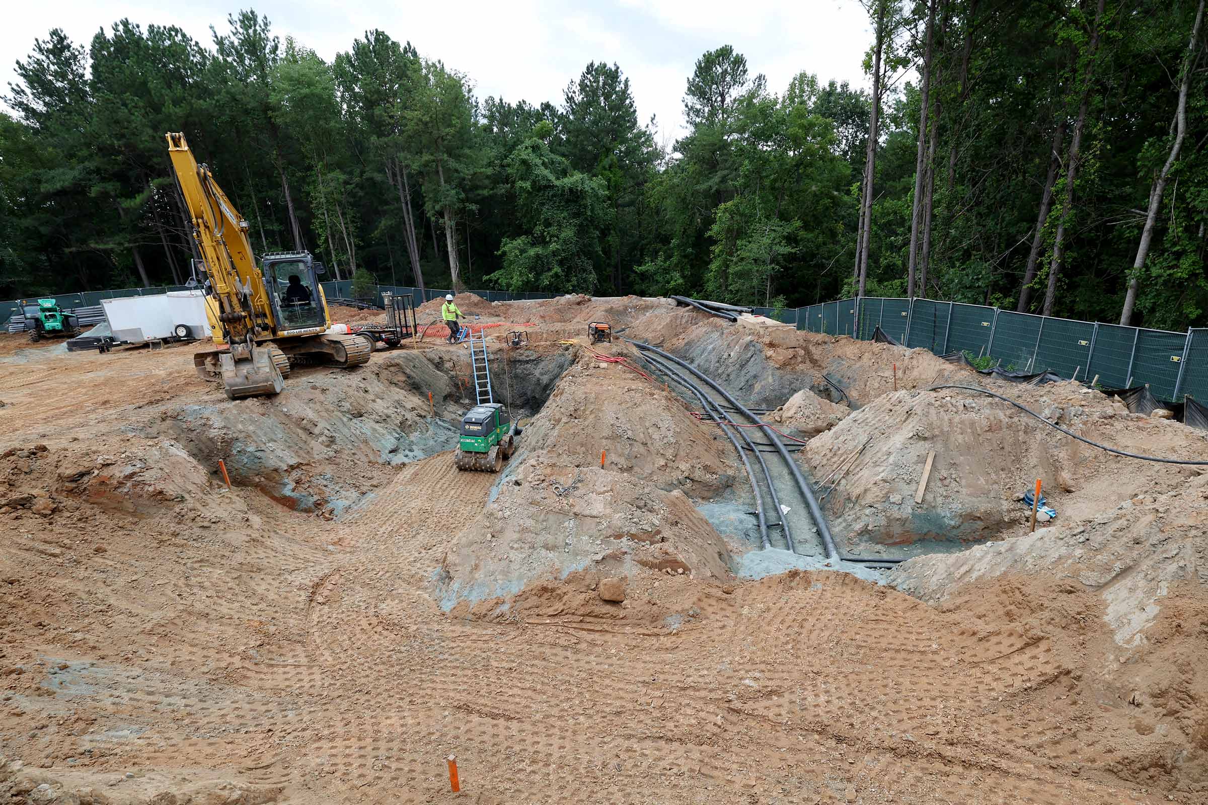 A digger and pipes are visible at the construction site.