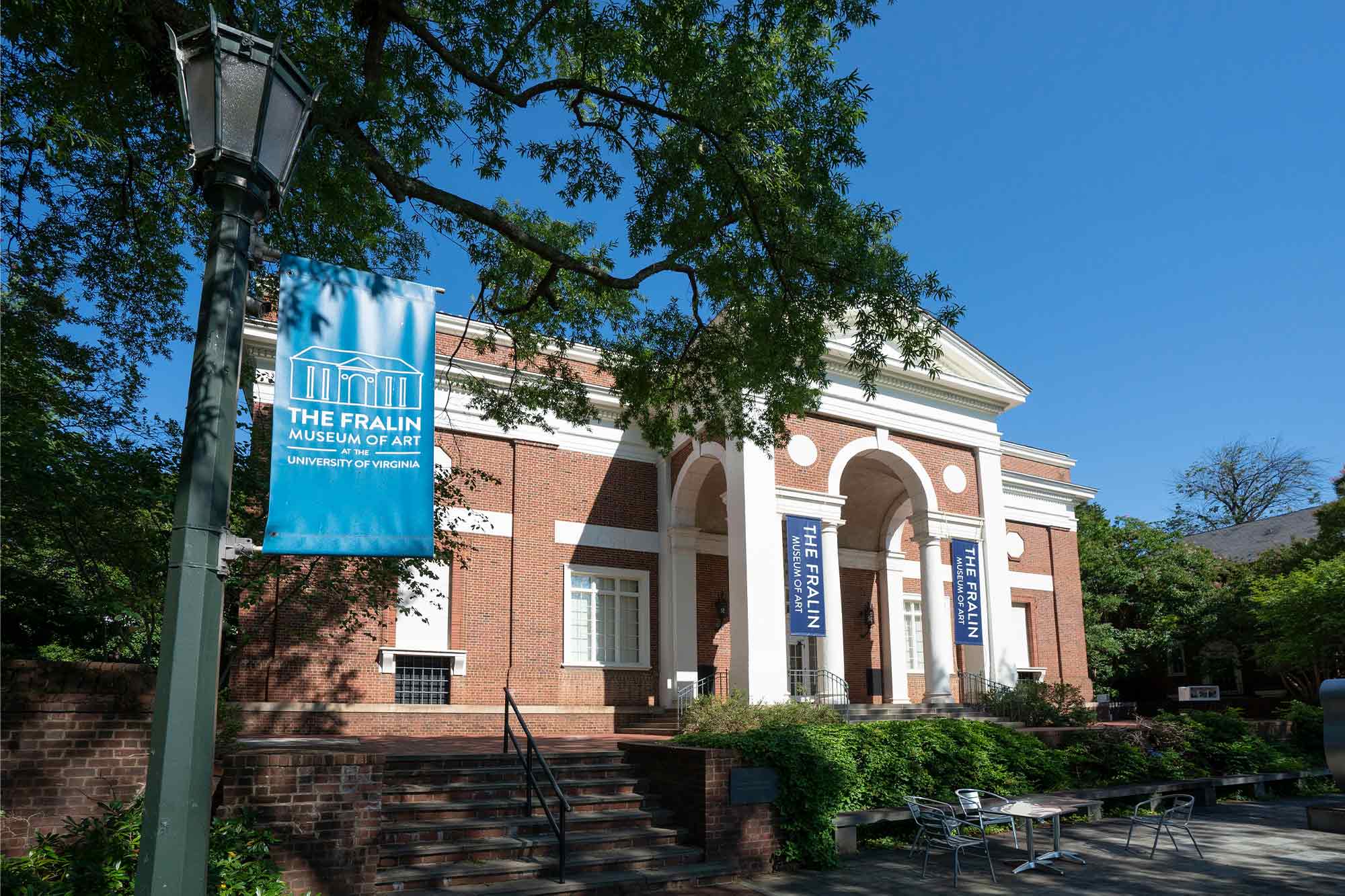 Exterior photo of The Fralin Museum. A light post in the foreground displays a banner that reads "The Fralin Museum of Art at the University of Virginia"