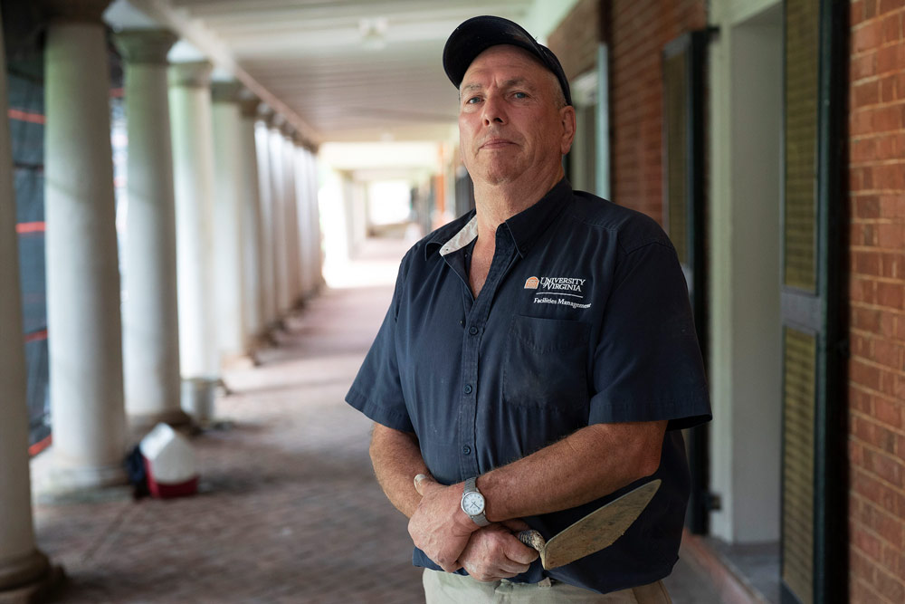 Tim Proffitt stands in front of the room on the lawn with this arms crossed. 