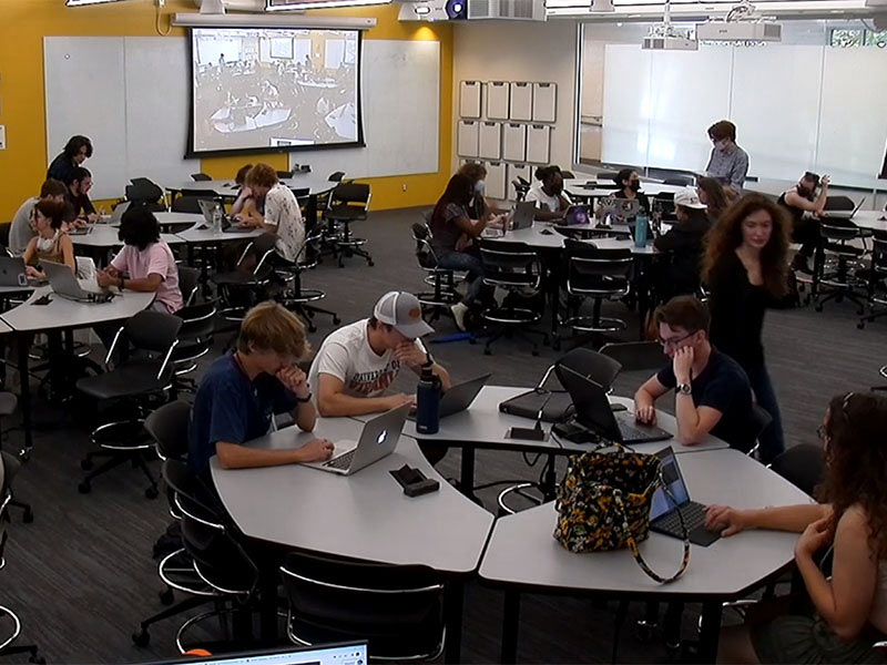 From above shot of a classroom of students with their heads down coding