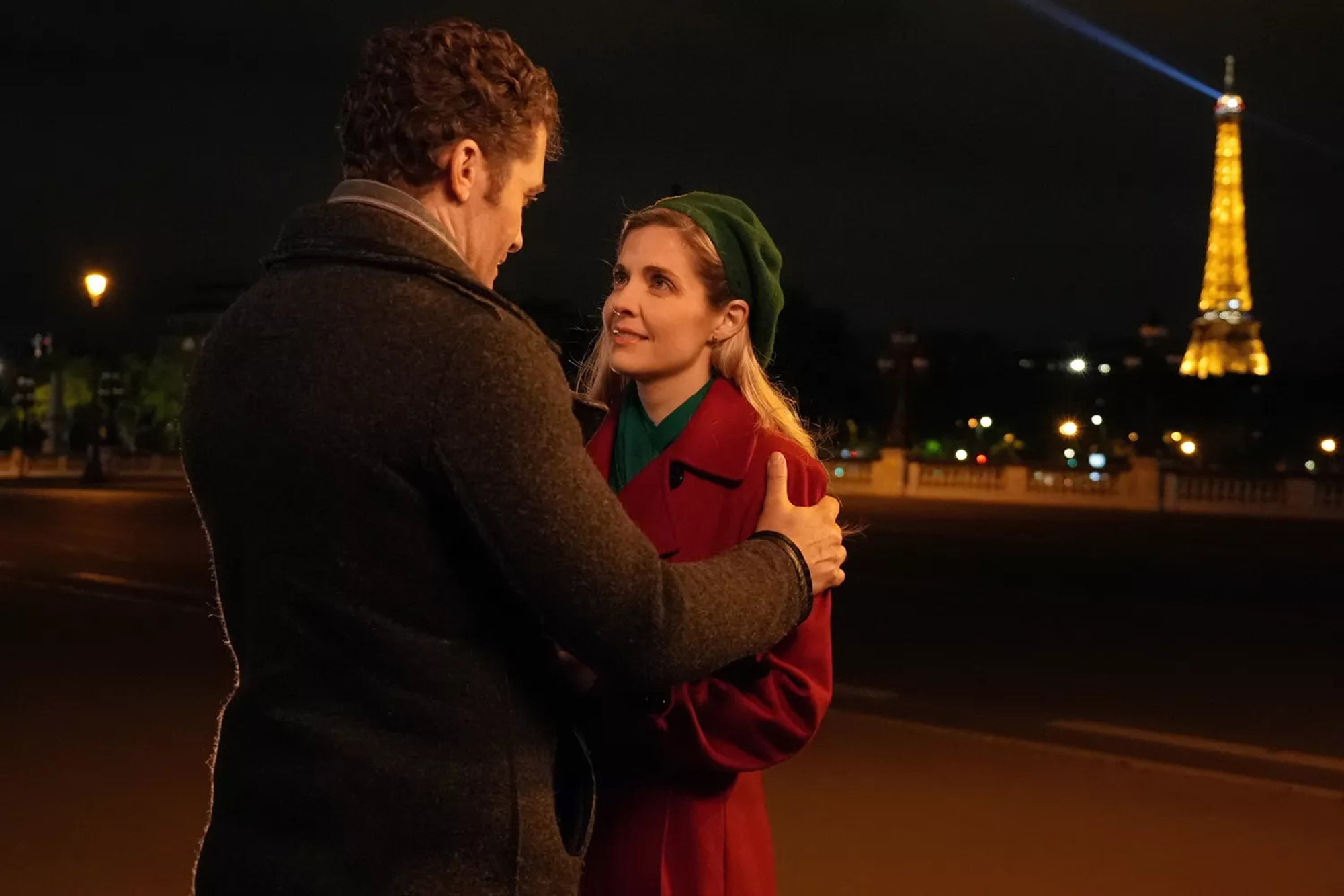 Movie frame featureing Jen Lilley standing with a leading man in Paris at night with the Eiffel Tower behind her