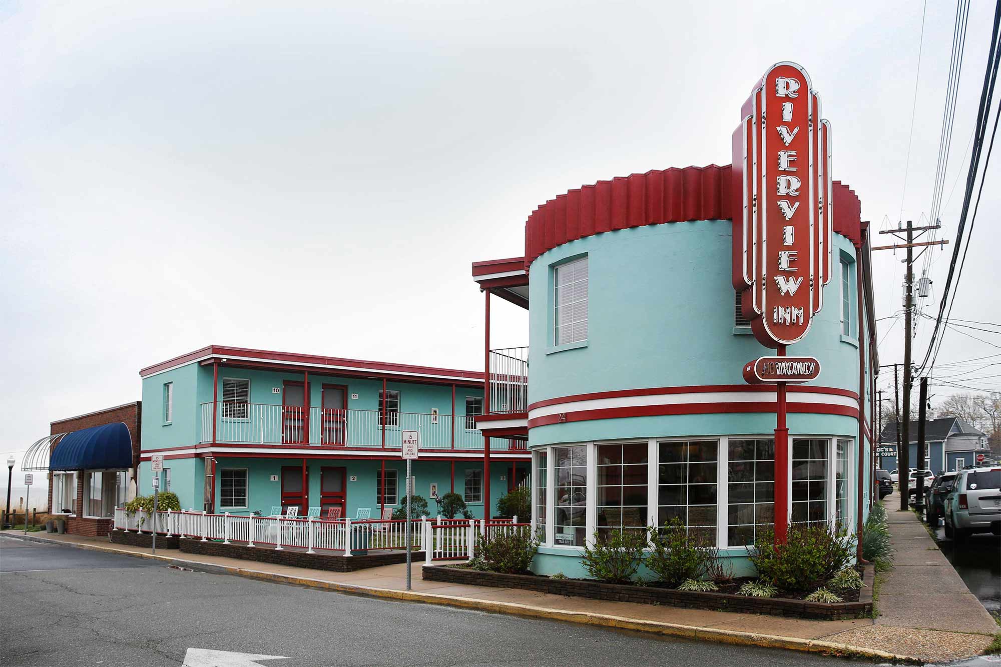 A 1950's style teal and red motel with a neon sign reading Riverview Inn
