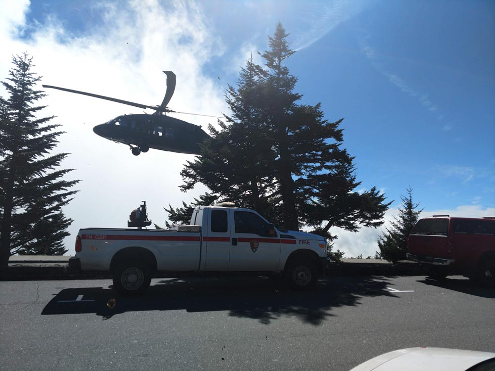 A helicopter flies above a fire department pickup truck
