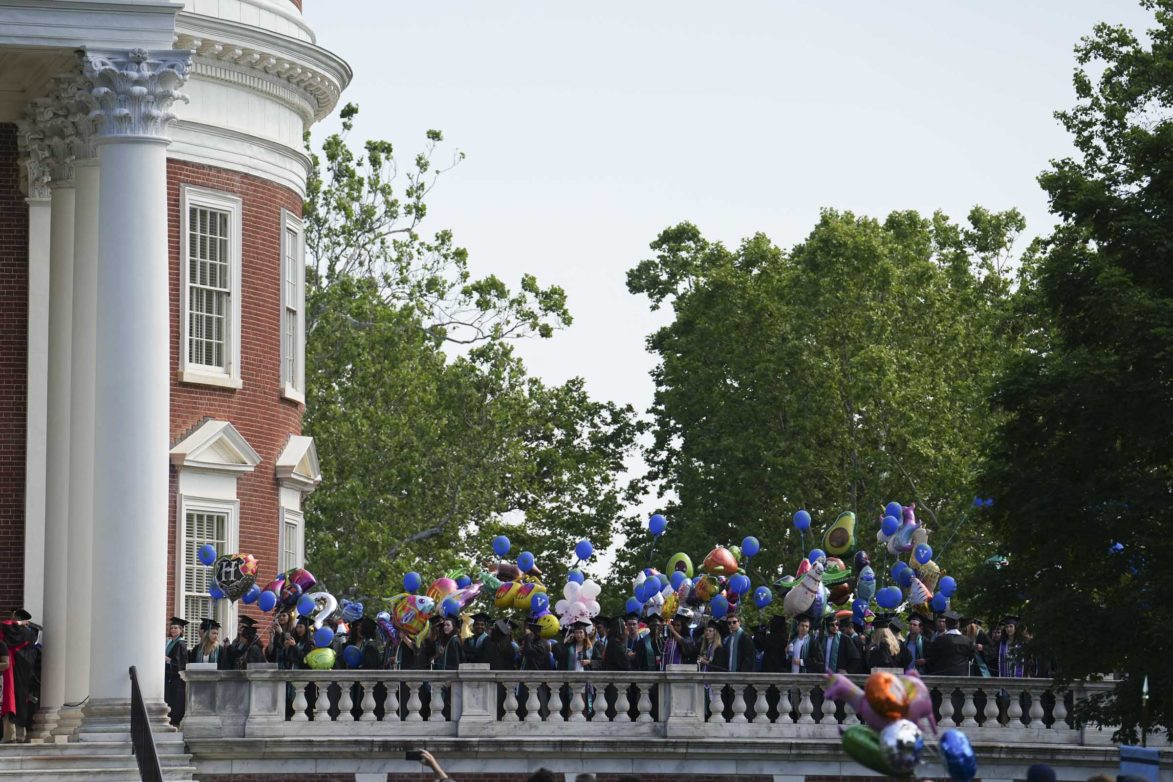 Dozens of students with balloons rising above them gather on the Rotunda’s plaza as they wait their turn to march down the Lawn.