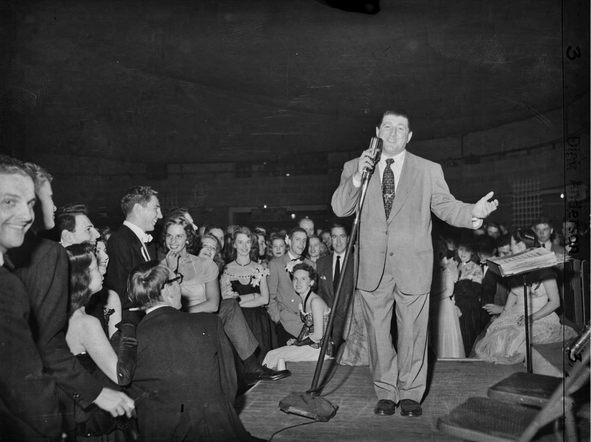 An old black and white photo of Tony Bennett singing on a stage at UVA