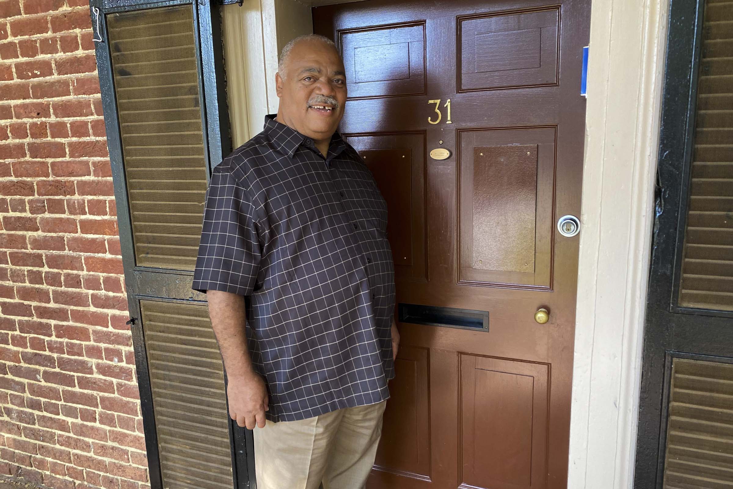 The father of a graduating student stands in front of the door to Lawn Room 31