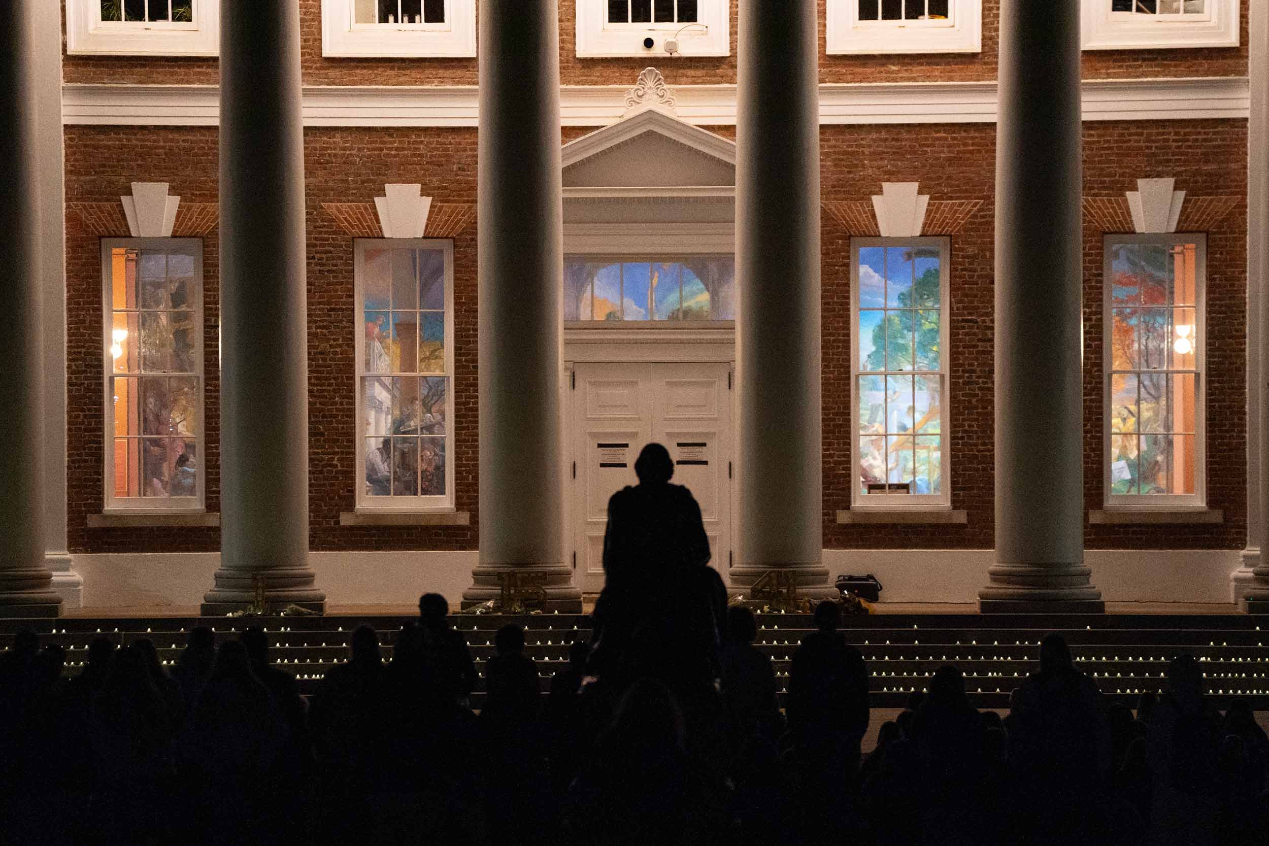 A view from behind the gathering of students and university community looking upon Old Cabell Hall during the candlelit memorial service