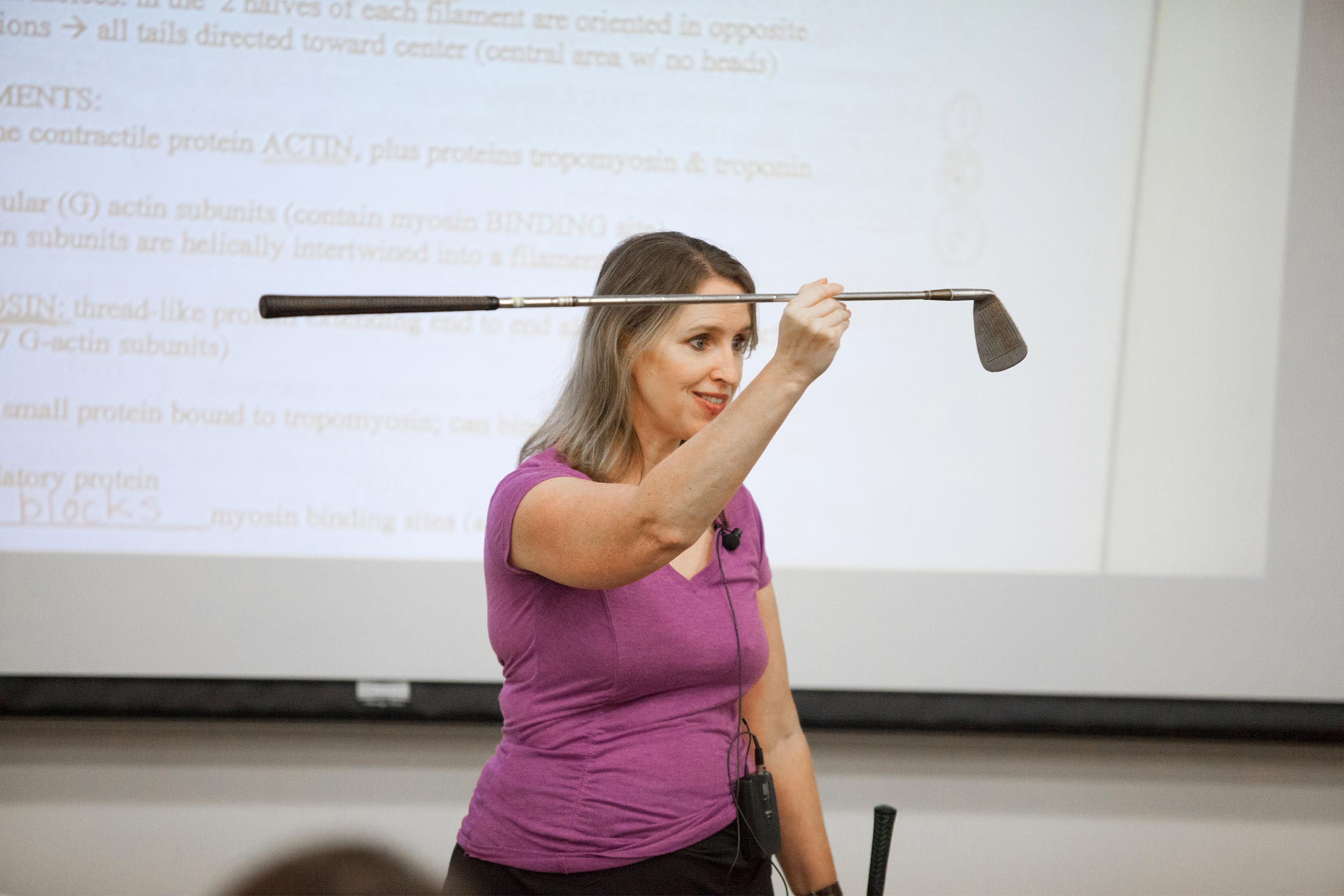 Christine Connelly giving a lecture holding a golf club