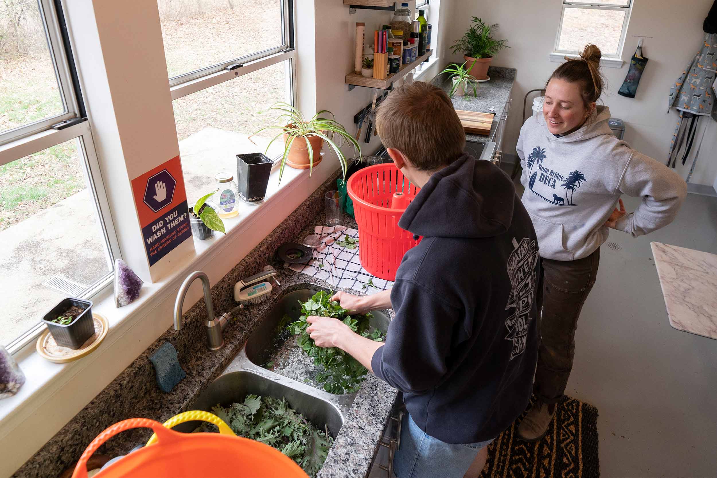 John Luecke, left, and Jayna Mallon, right, in a kitchen washing vegetables