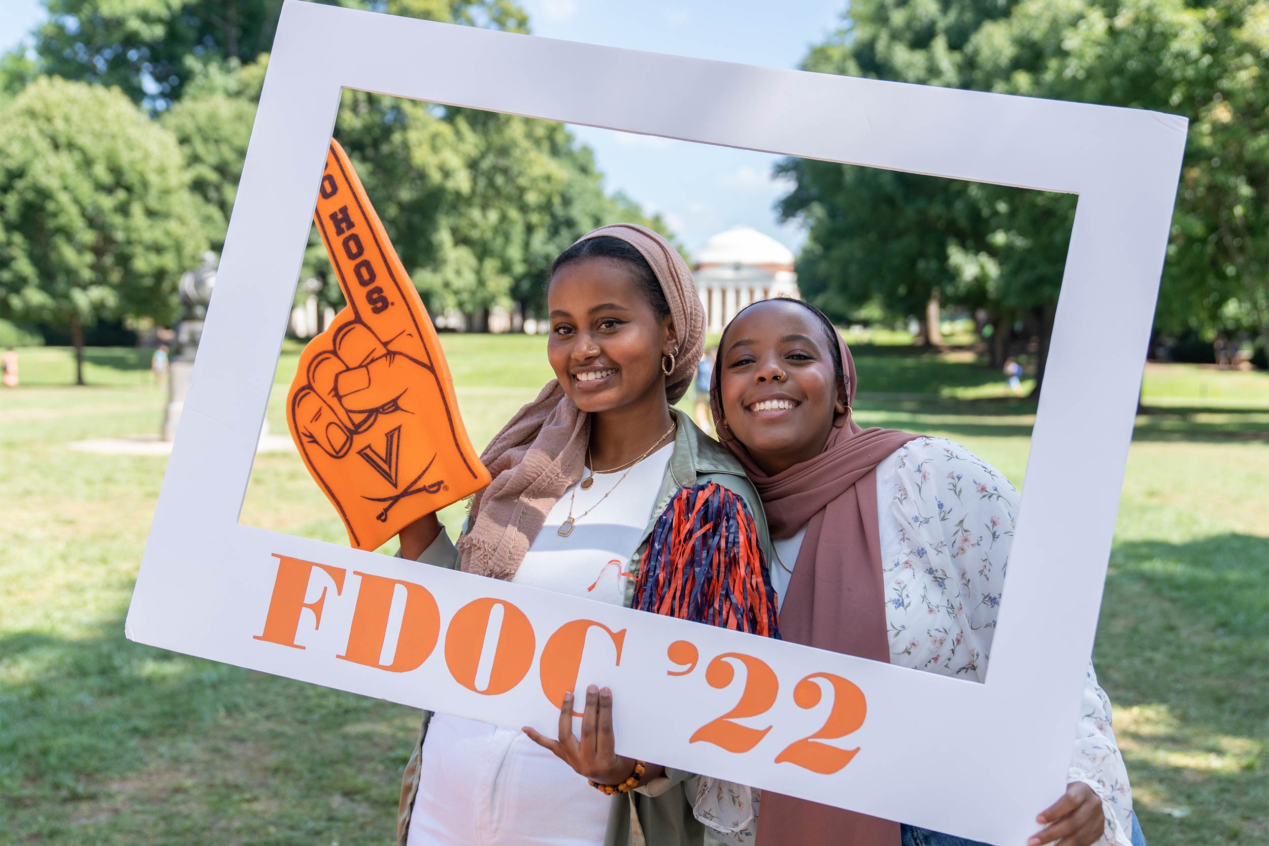 Two smiling students hold a frame reading FDOC '22 and pose for a portrait in front of the Rotunda