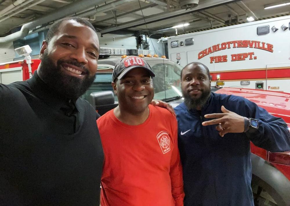 Three men pose for a portrait in front of a Charlottesville Fire Department ambulance