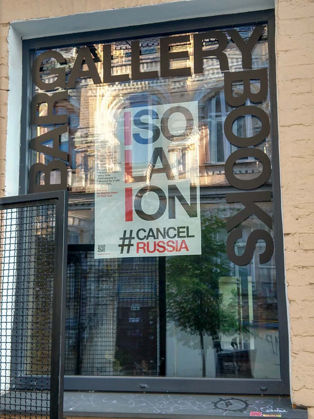 In an art gallery window hangs a poster reading 'Isolation #CancelRussia'