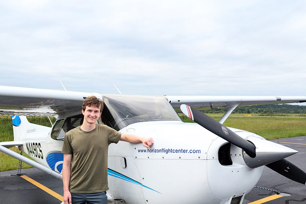 Will Crouch posing for a photo with a single engine plane.