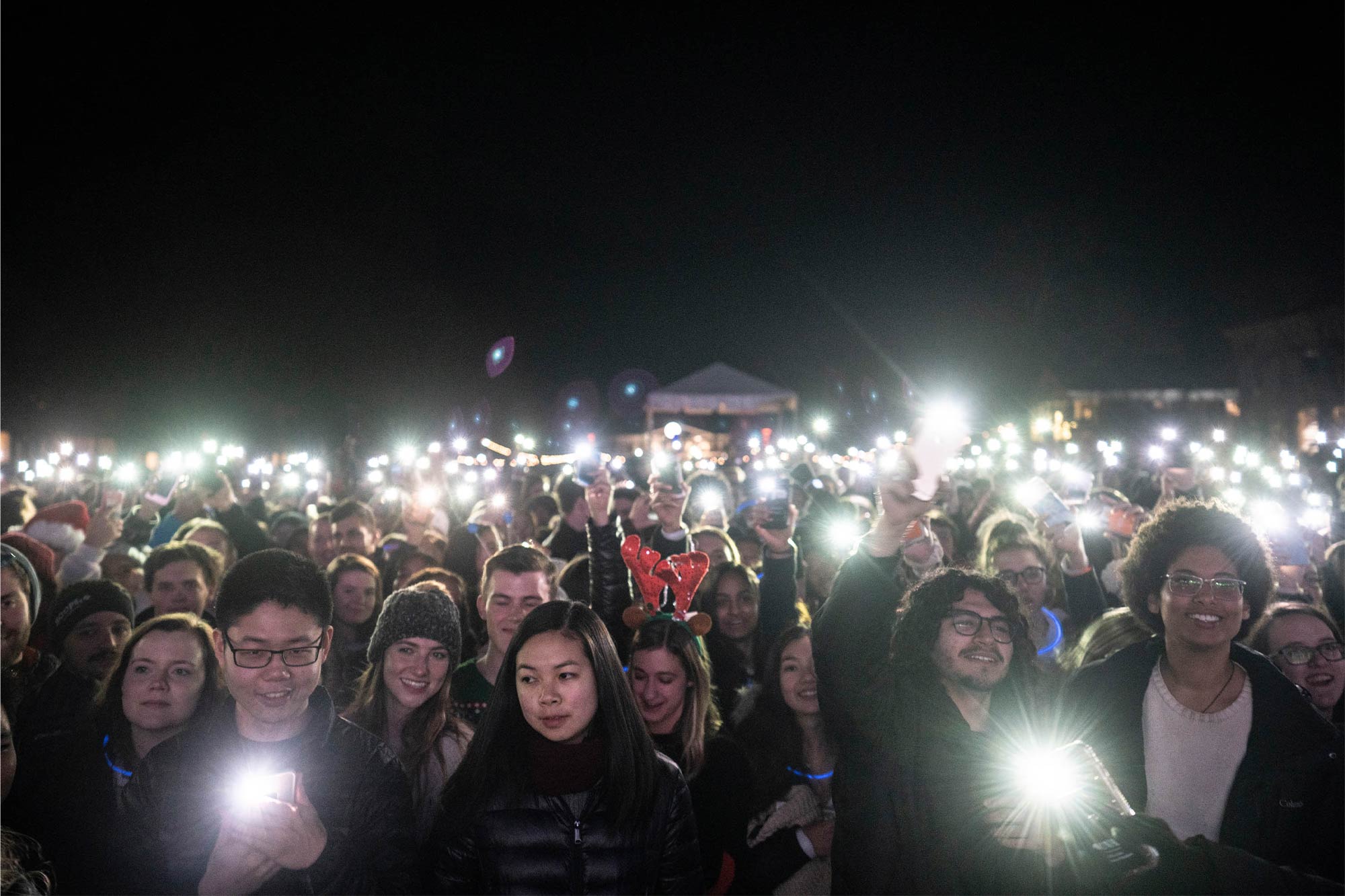 A large group of students in the dark holding lights