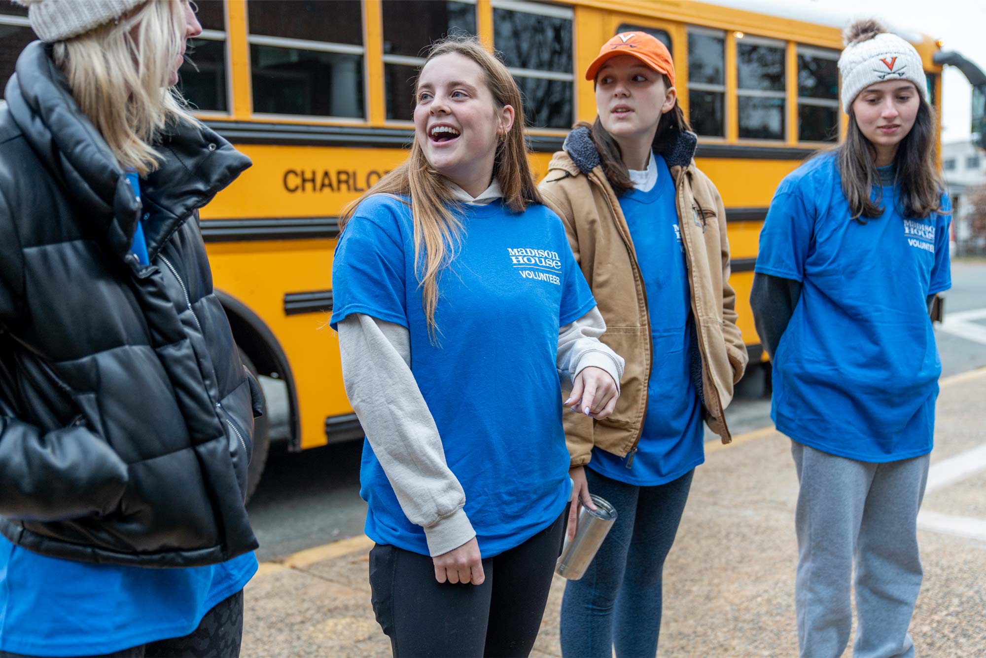UVA students from left to right, Brianna Devine, Rachel Moore, Ellie Stombres and Kelly Shirer laughing in front of a bus
