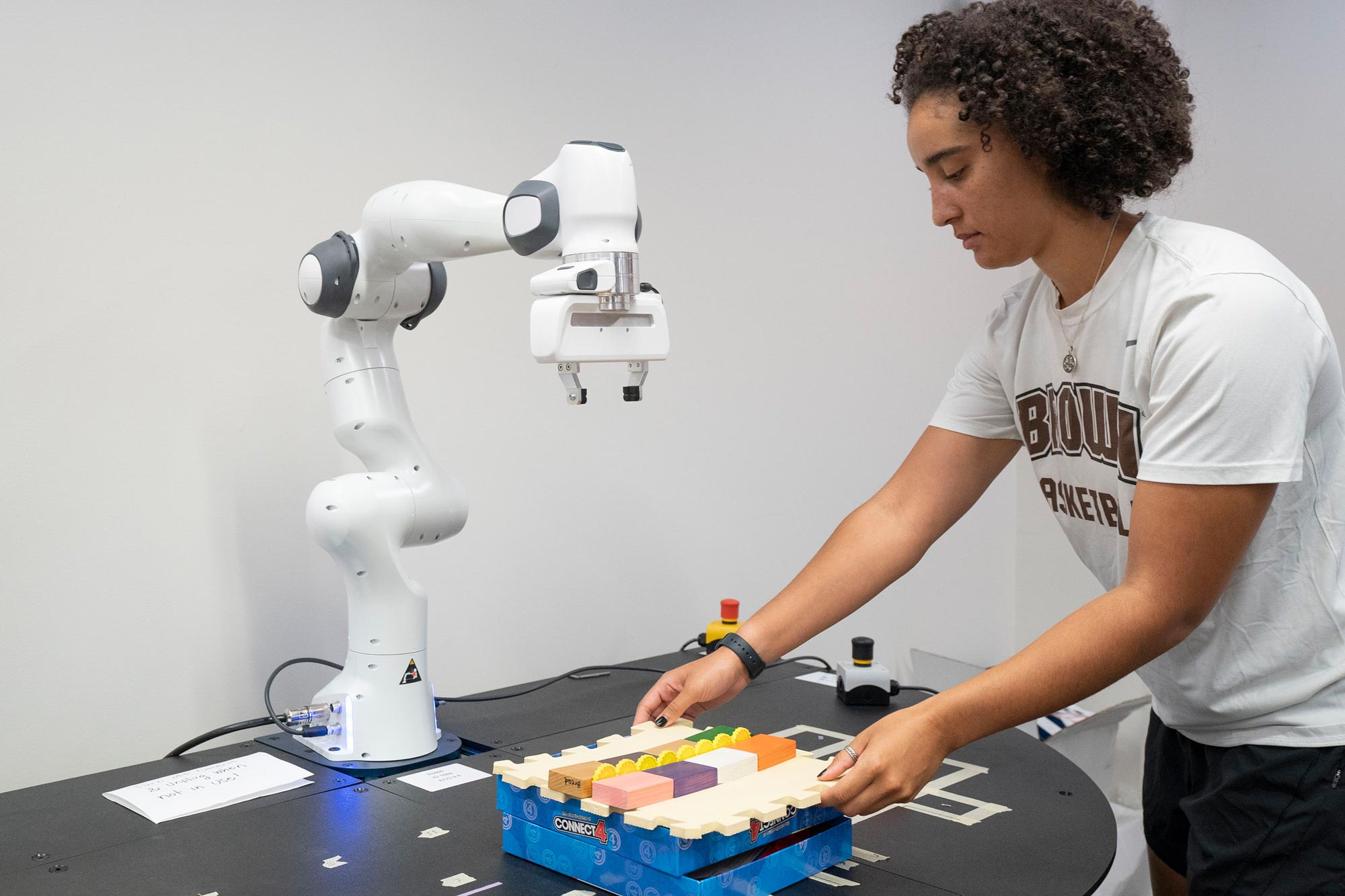 Haley Green placing a tray of color blocks in front of a robot