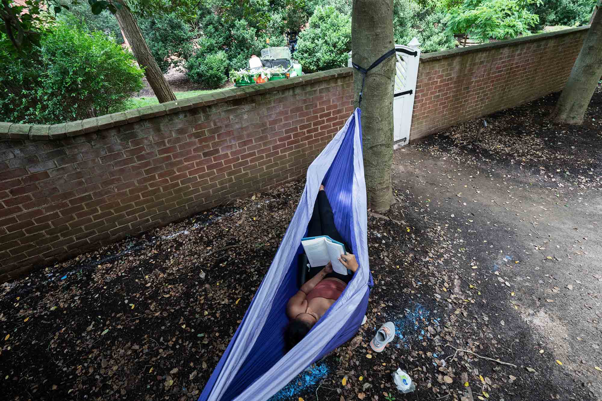 A woman reads a book while lying in a hammock