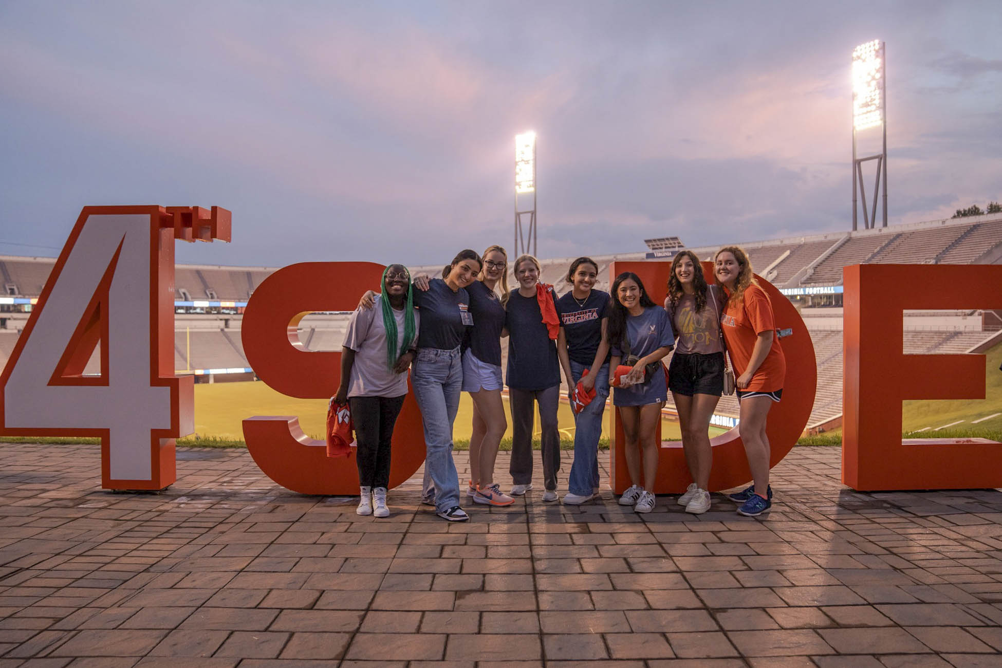 A group of students pose for a group shot in front of large block letters reading 4th SIDE