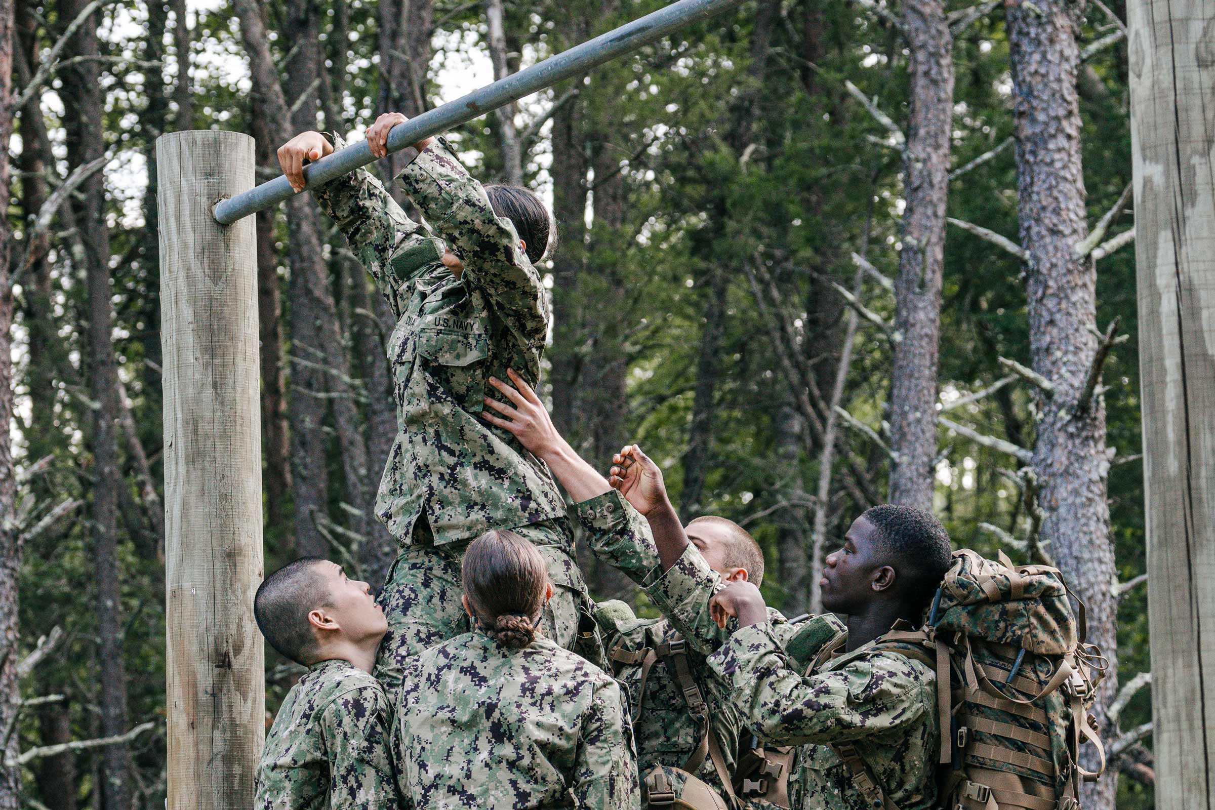 Candid photo of demonstrating teamwork as they assisted each other over the barriers in the obstacle course.