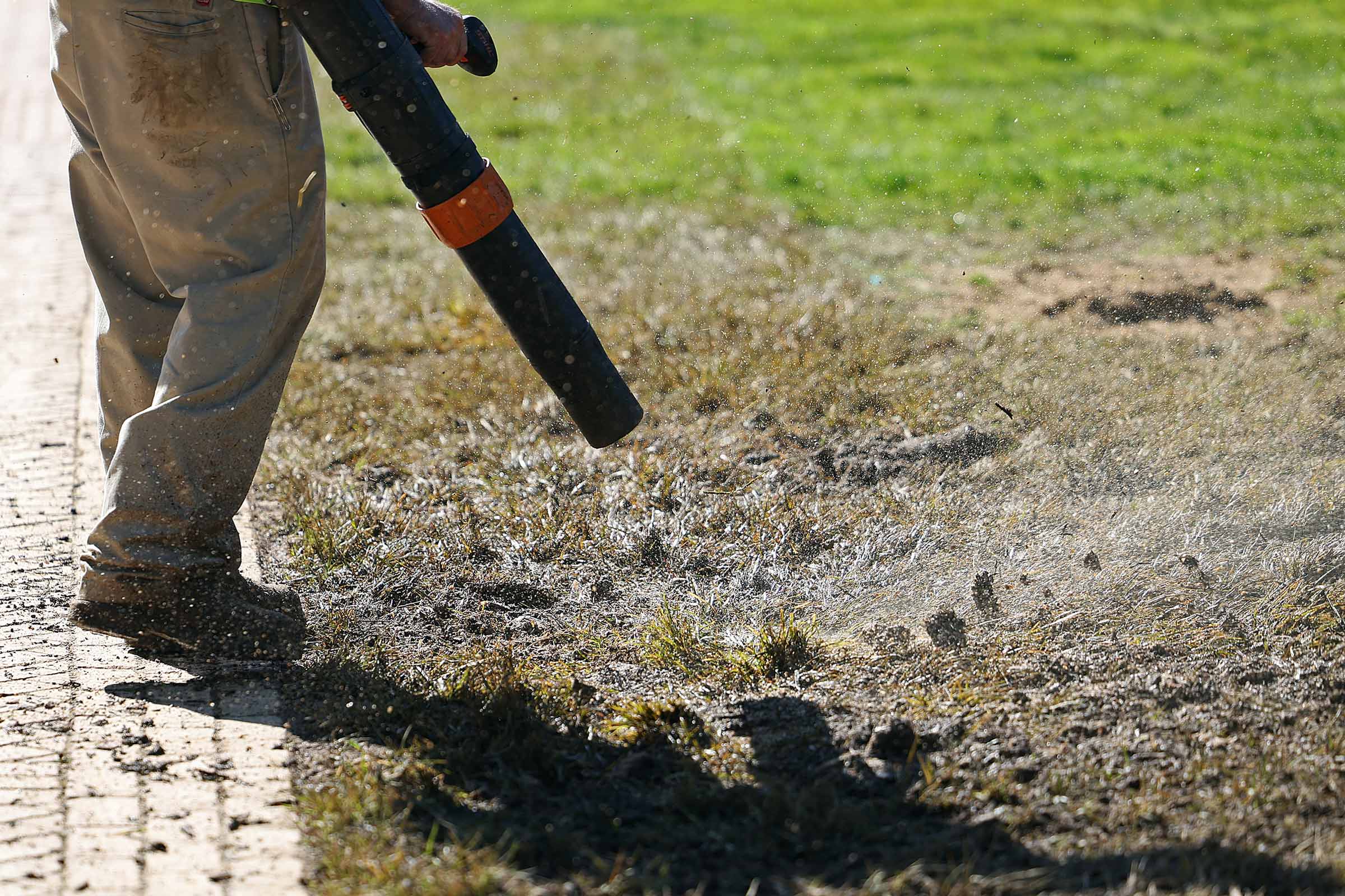 A member of the Facilities Management team drying out the Lawn with a leaf blower