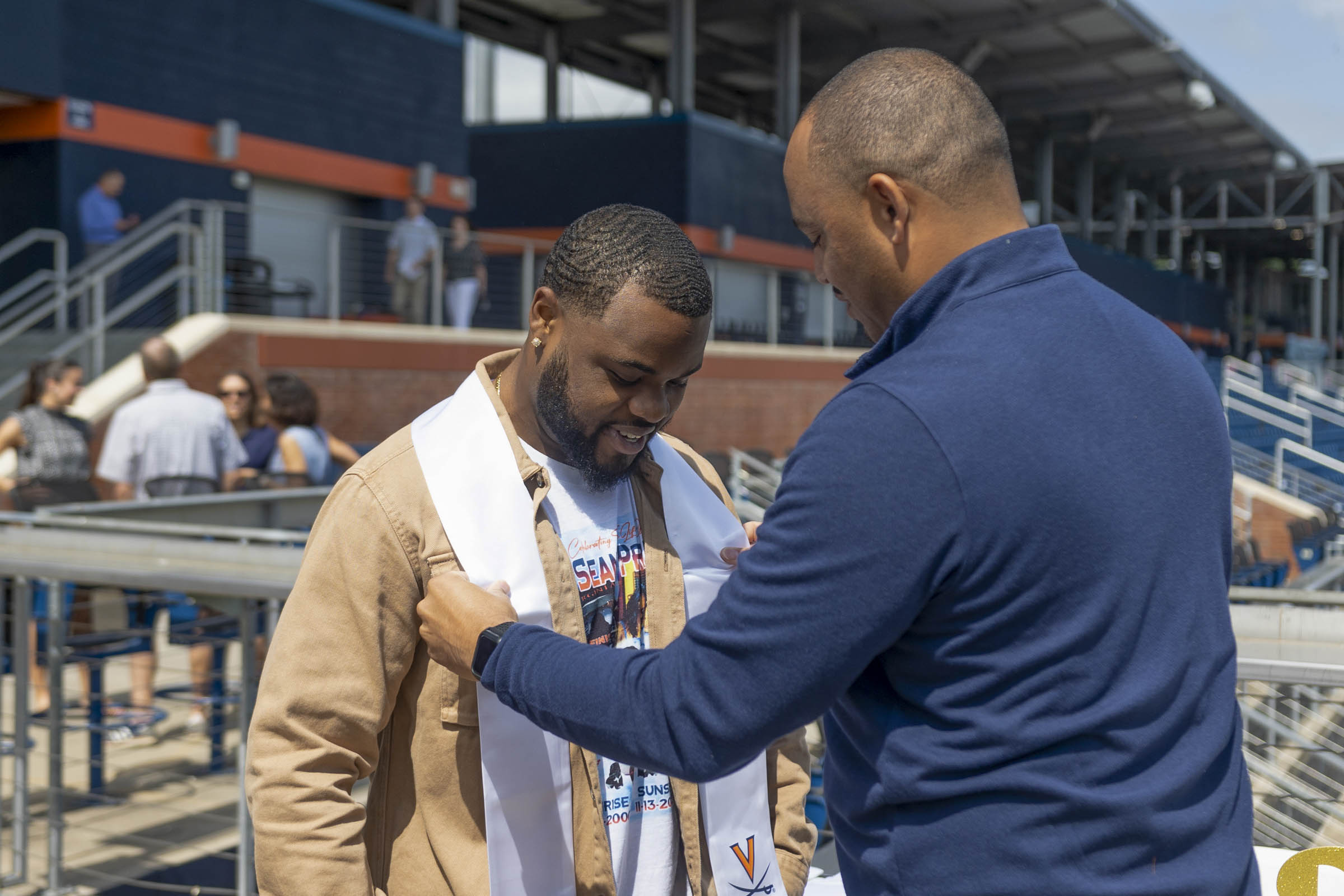 Candid of Mike Hollins recieving his student athlete graduation stole from coach Tony Elliott