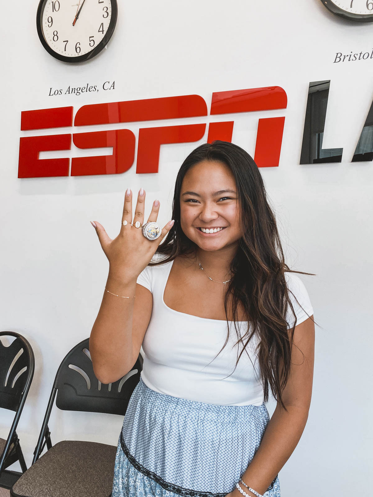 In front of a backdrop reading ESPN, Khuyen Dinh holds up her hand to display a large ring.