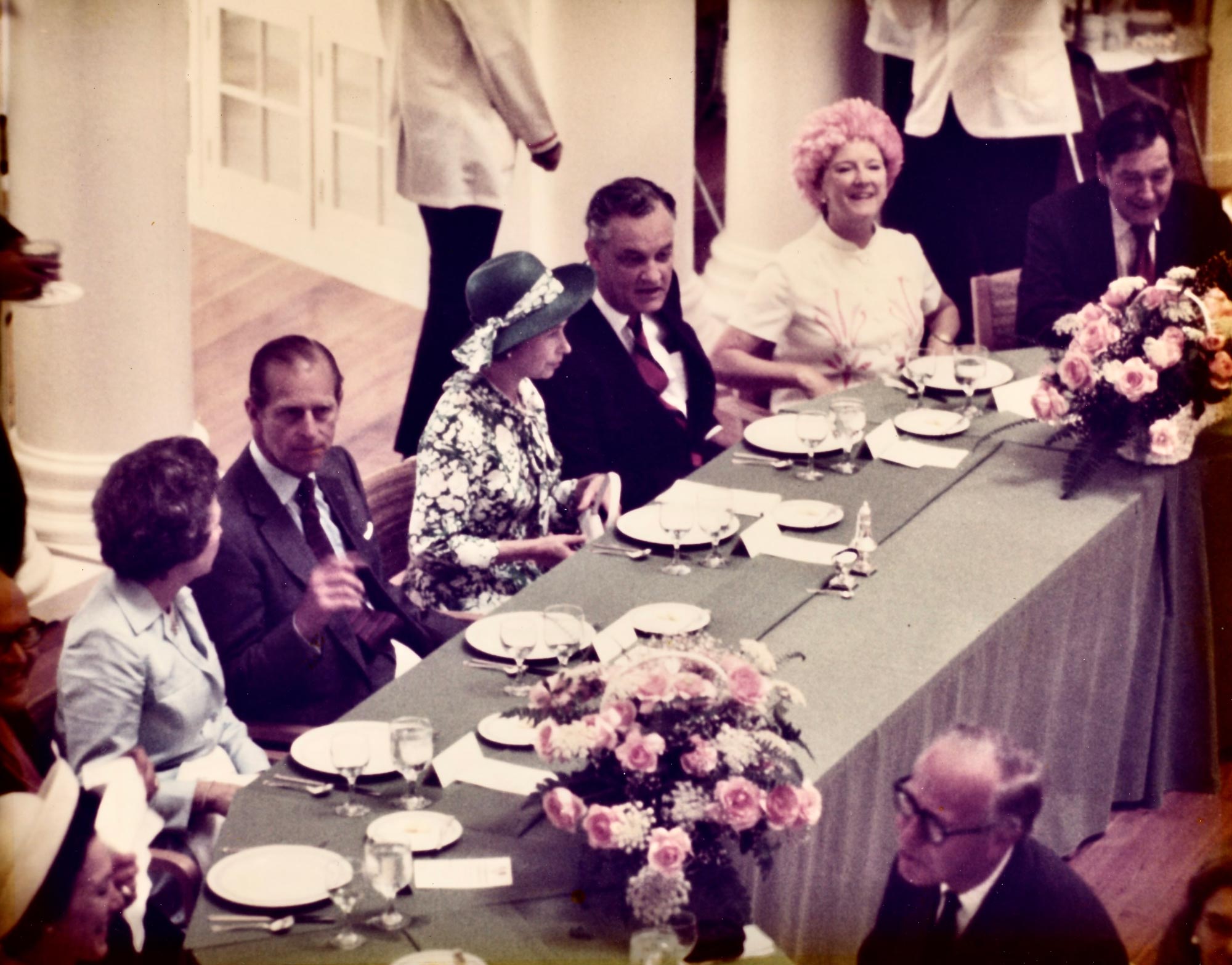 Queen Elizabeth sits at a banquet table with several other people chatting