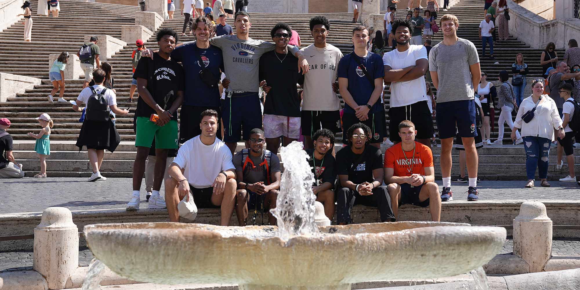 The basketball team poses for a group photo in front of a fountain. 