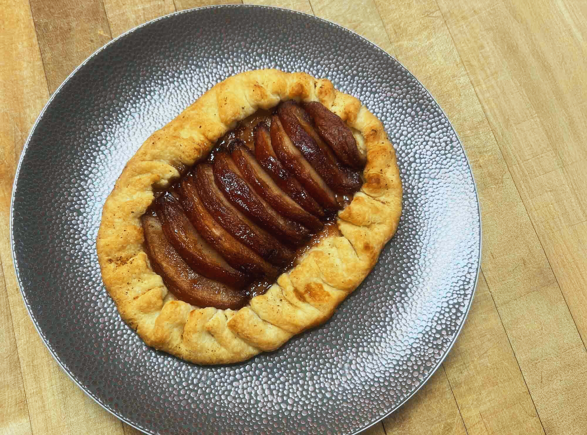 A pastery crust filled wiht red wine poached apples on a silver plate