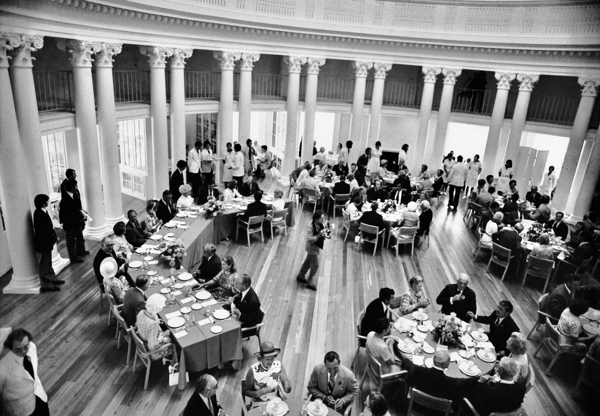 From the top floor of the Rotunda Dome Room, people are seated at several large banquet tables and serving staff line the back wall
