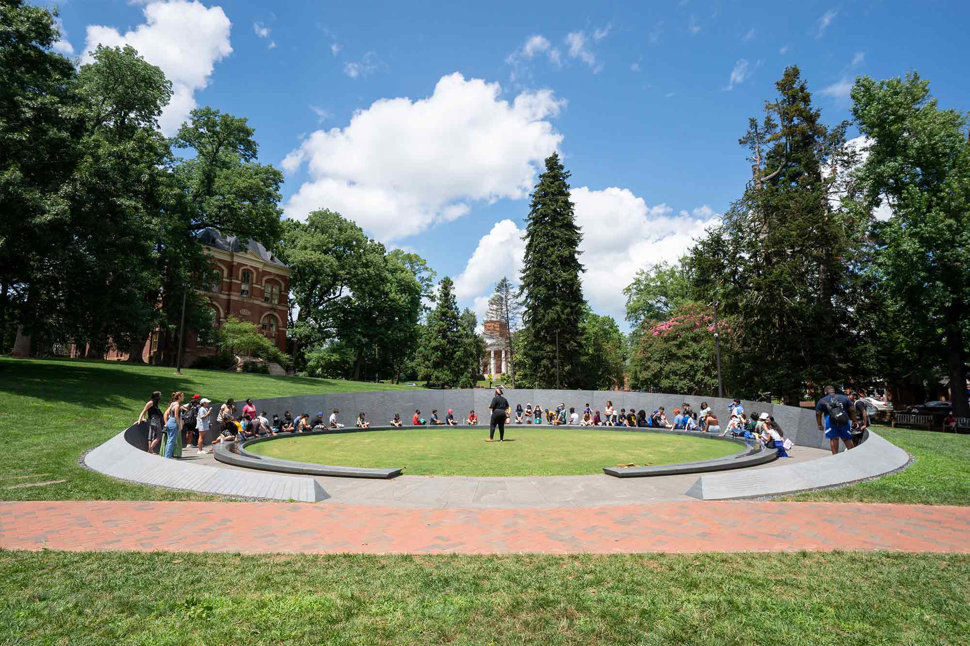 A crowd of students fills a ring inside the Memorial to Enslaved Laborers
