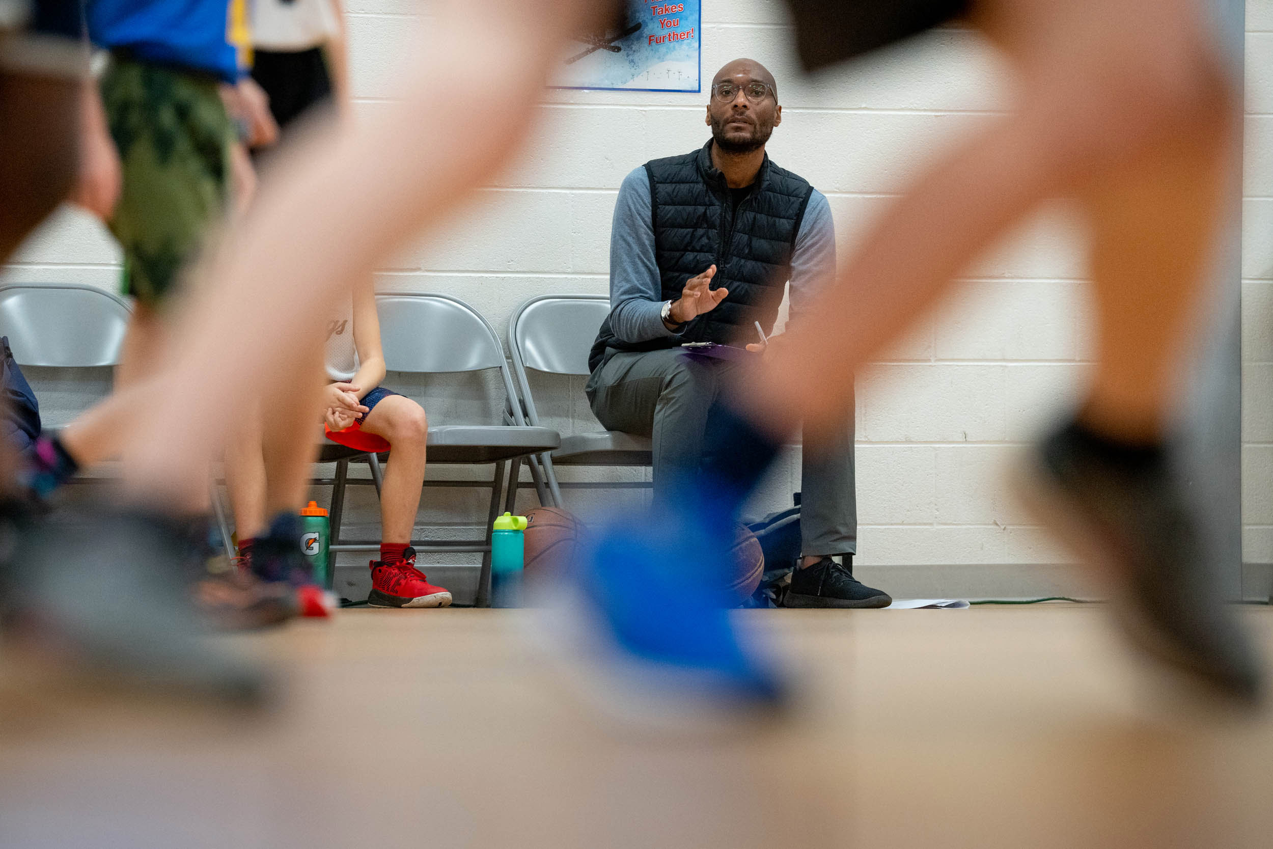 Dr. Taison Bell sitting on the sidelines coaching an elementary school basketball team