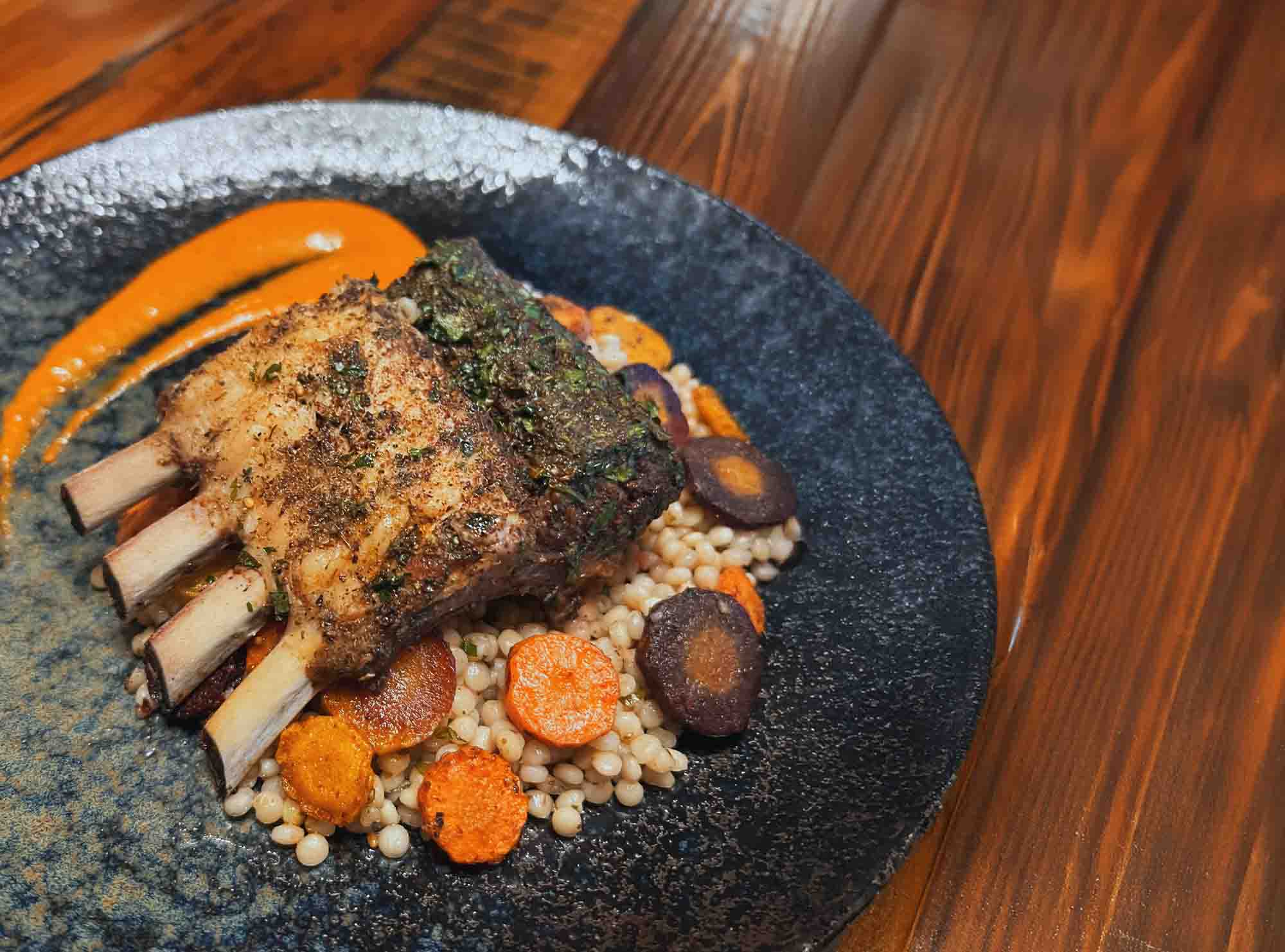 A rack of lamb with carrots on a bed of couscous