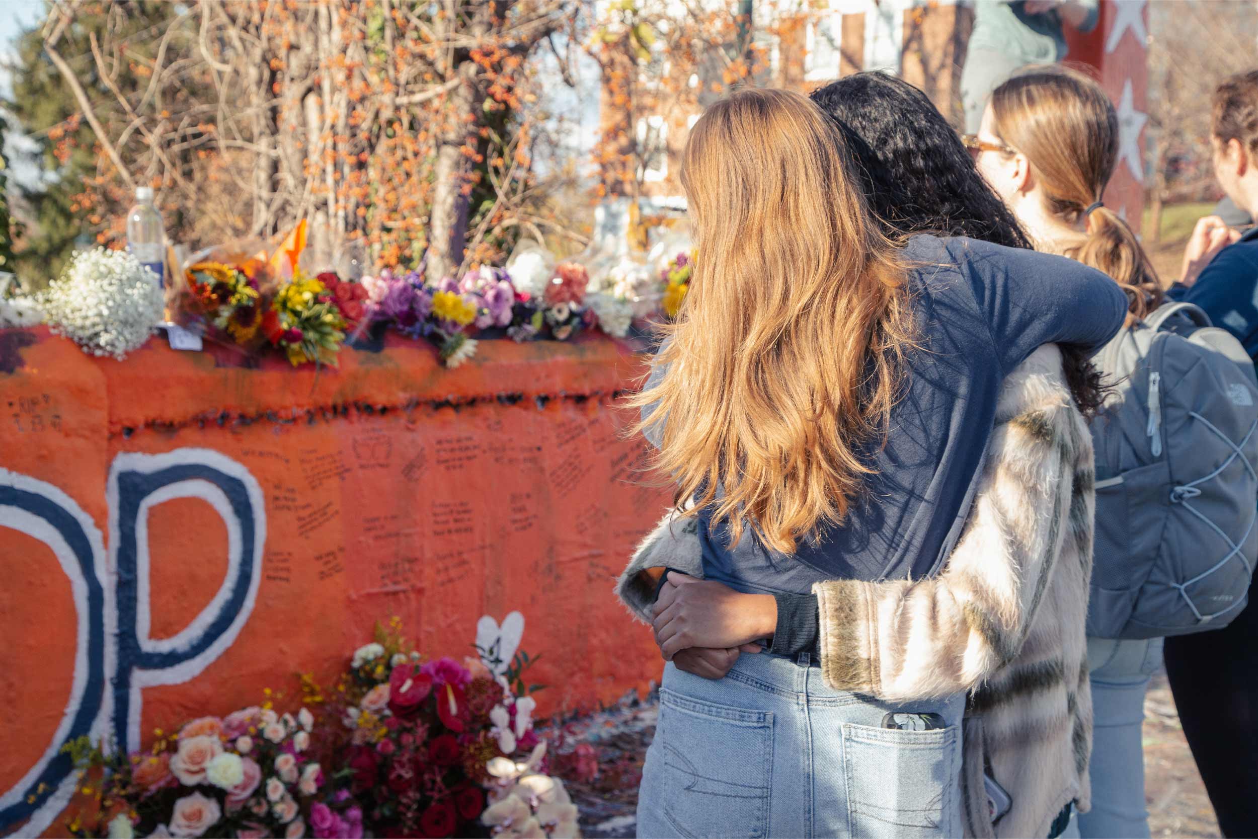 Two students hug as they look at the Beta Bridge Memorial