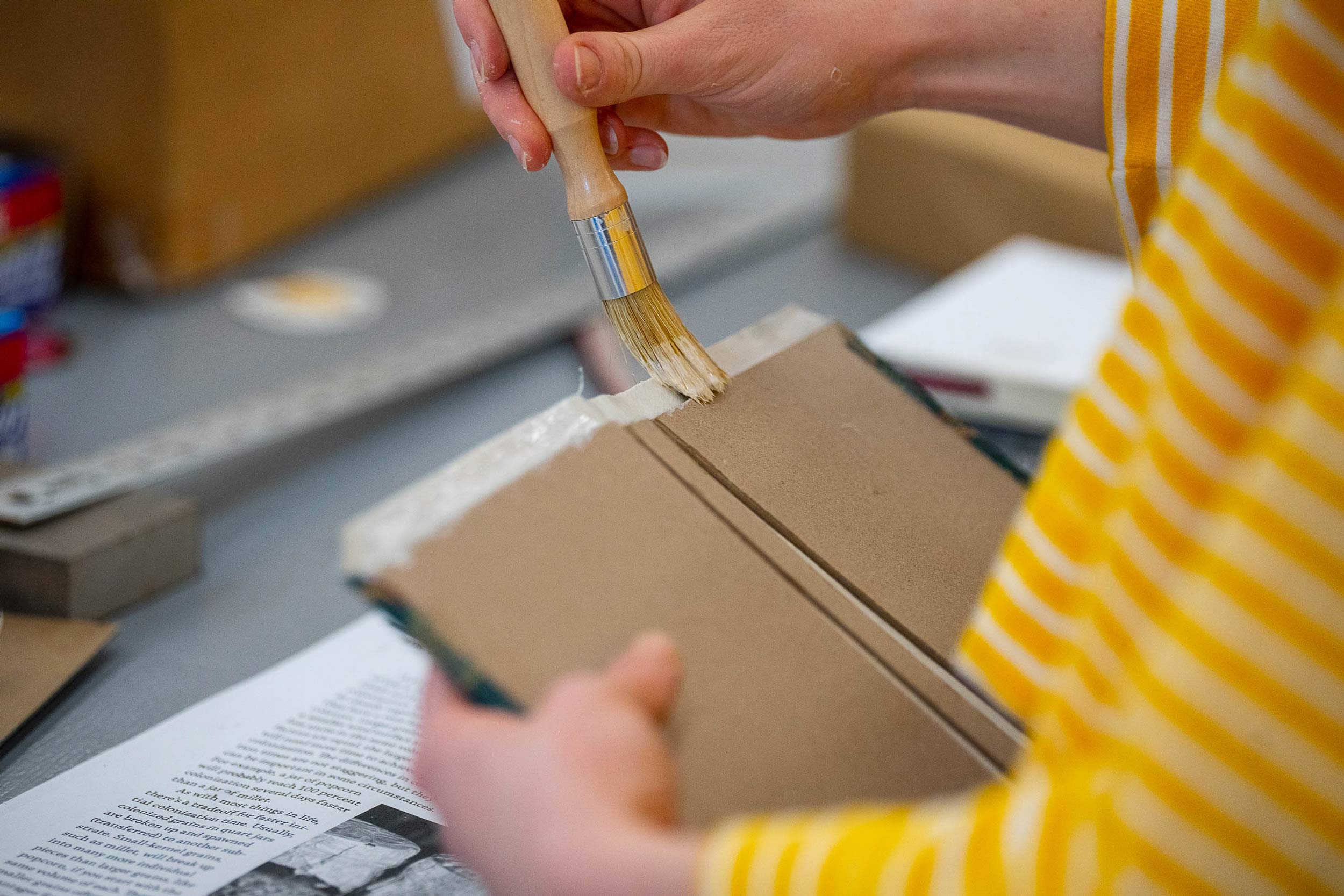 Close up of hands applying glue to a book binding