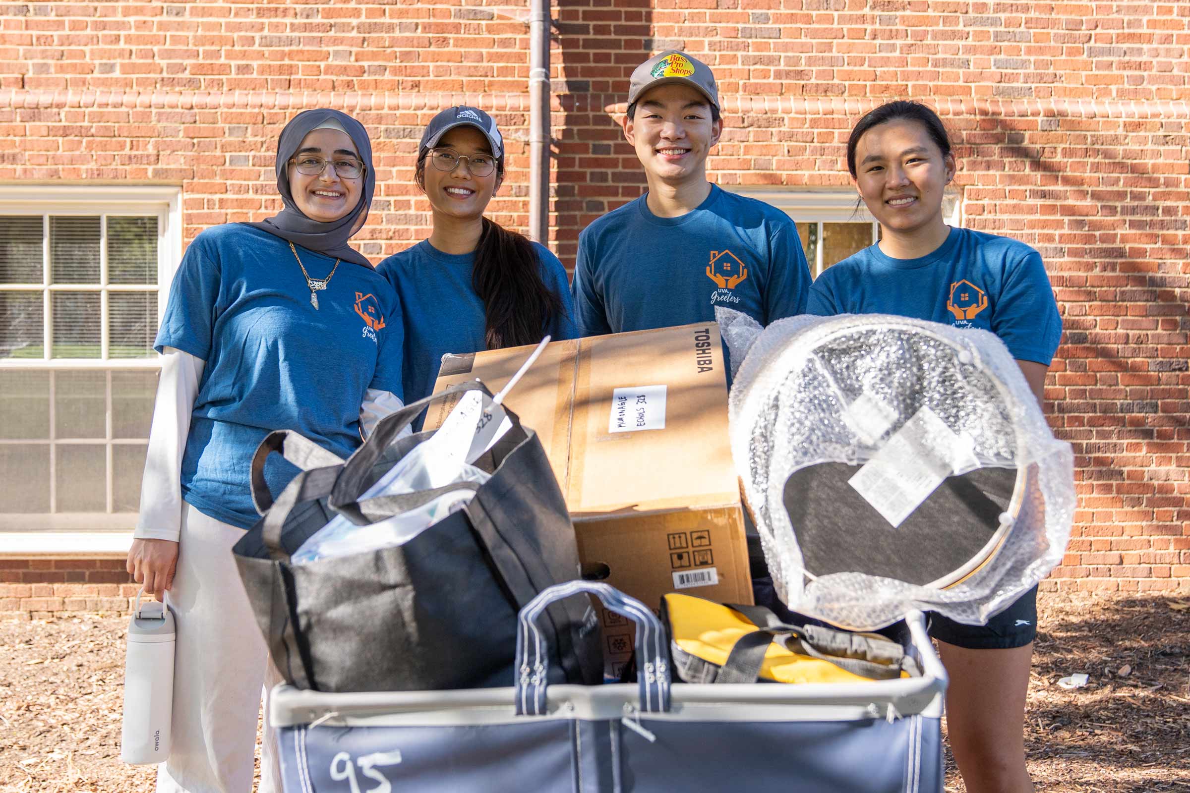 A family gathers behind a UVA cart of belongings and smiles for the camera