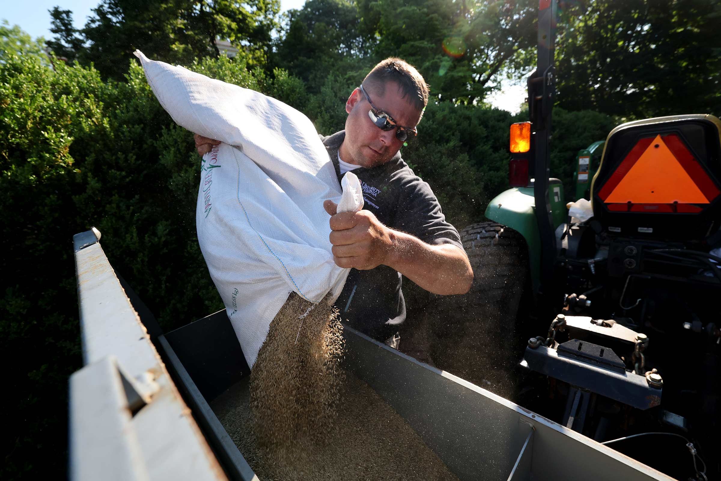 Turf supervisor Jonathan Racey loads fast-germinating rye grass seed into a seeder. 