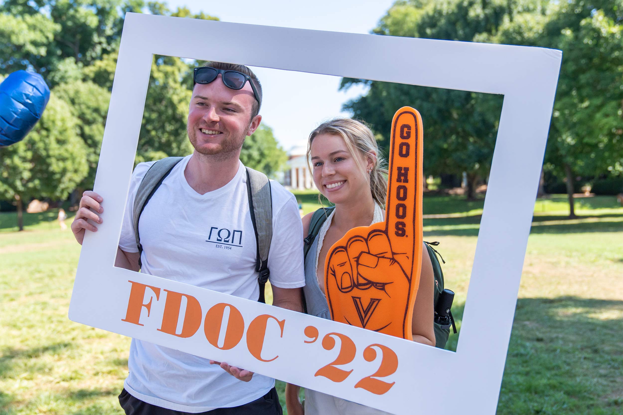 Two smiling students hold the FDOC '22 frame and smile with the Rotunda in the background