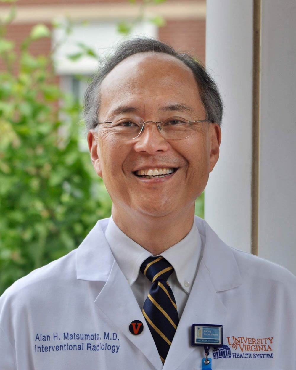 Alan Matsumoto, wearing a white coat, smiles for the camera
