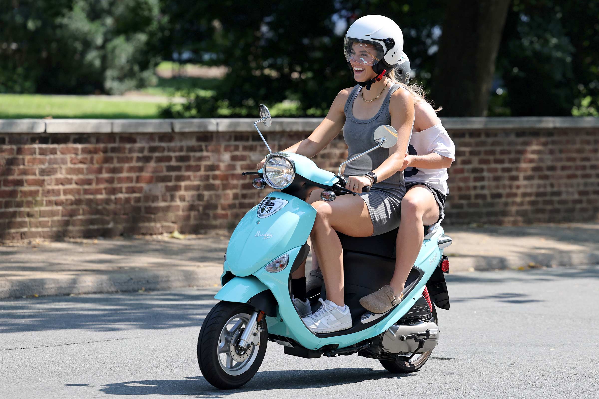 Girl riding a moped with another girl sitting behind her.