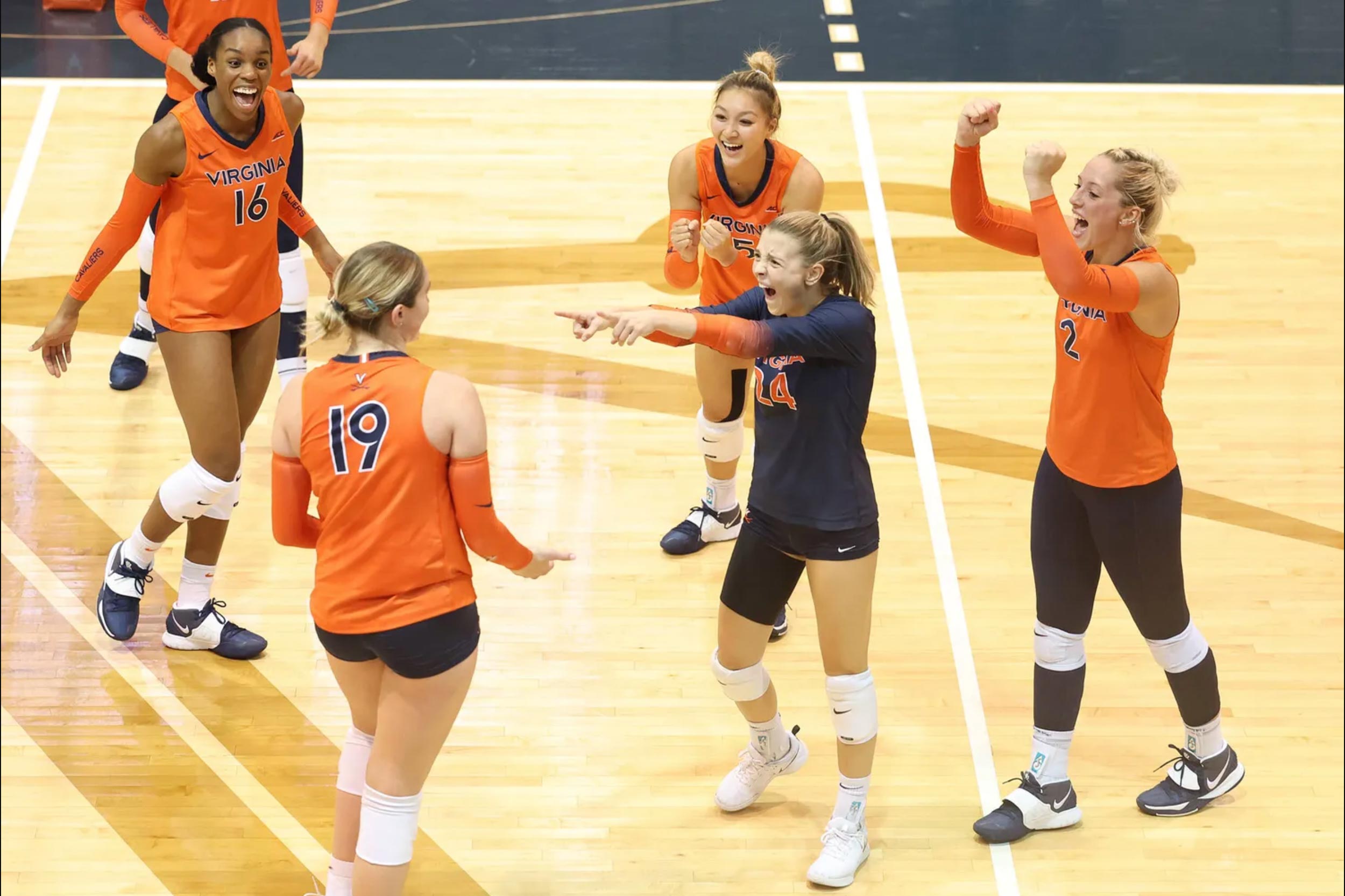 UVA volleyball players on the court celebrating